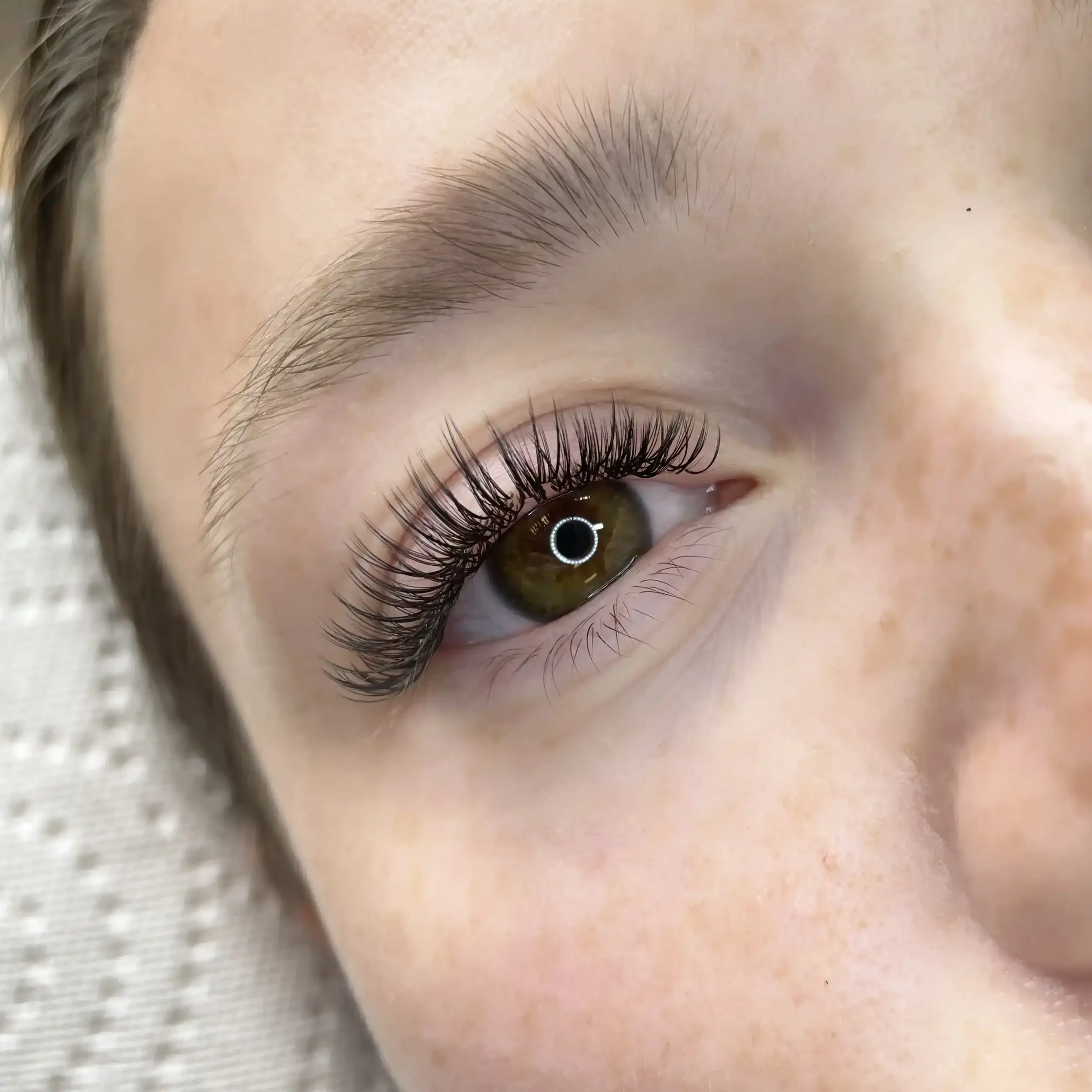Close-up of a woman's eye with long, curled eyelashes and a brown iris.