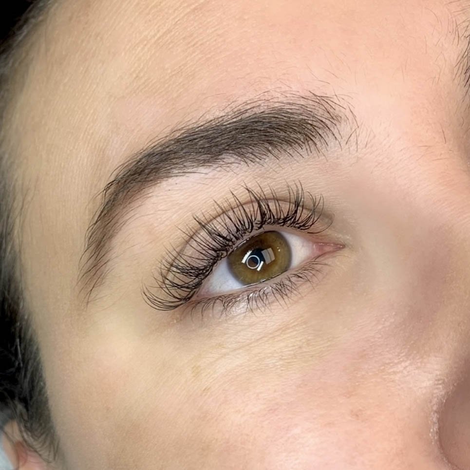 Close-up of a person's eye with long, curled eyelashes and well-groomed eyebrows.