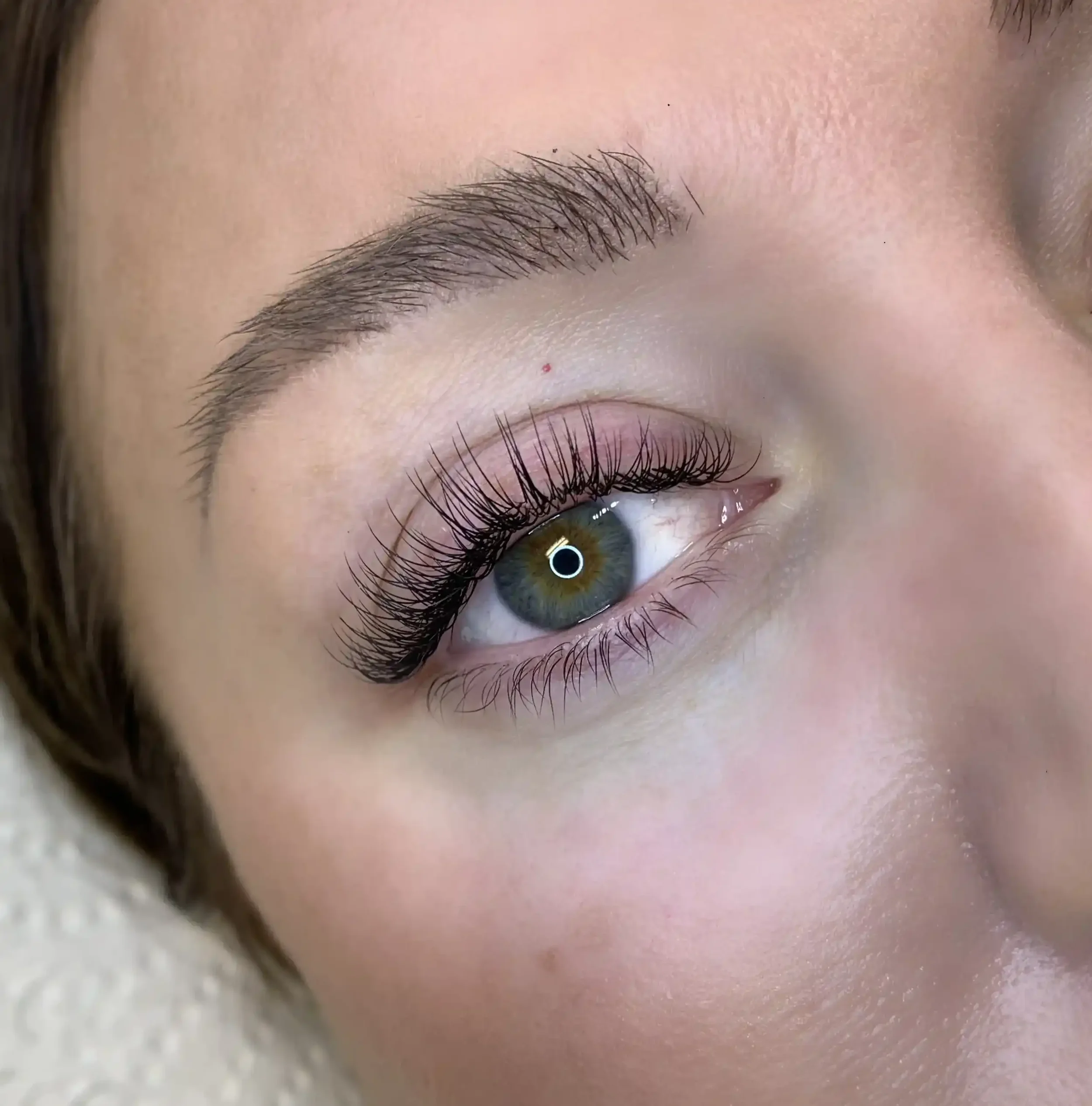 Close-up of a woman's eye with long eyelashes, well-groomed eyebrow, and smooth skin.