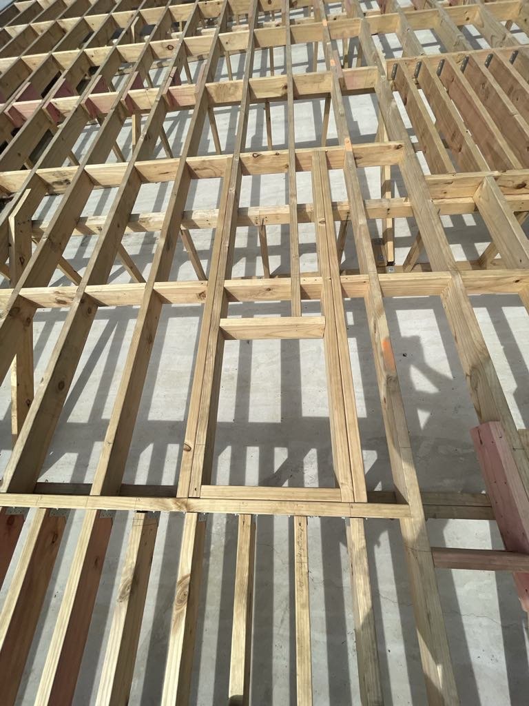 Wooden framing structure for a building under construction, with multiple beams and supports creating a grid pattern with superior structural standard.