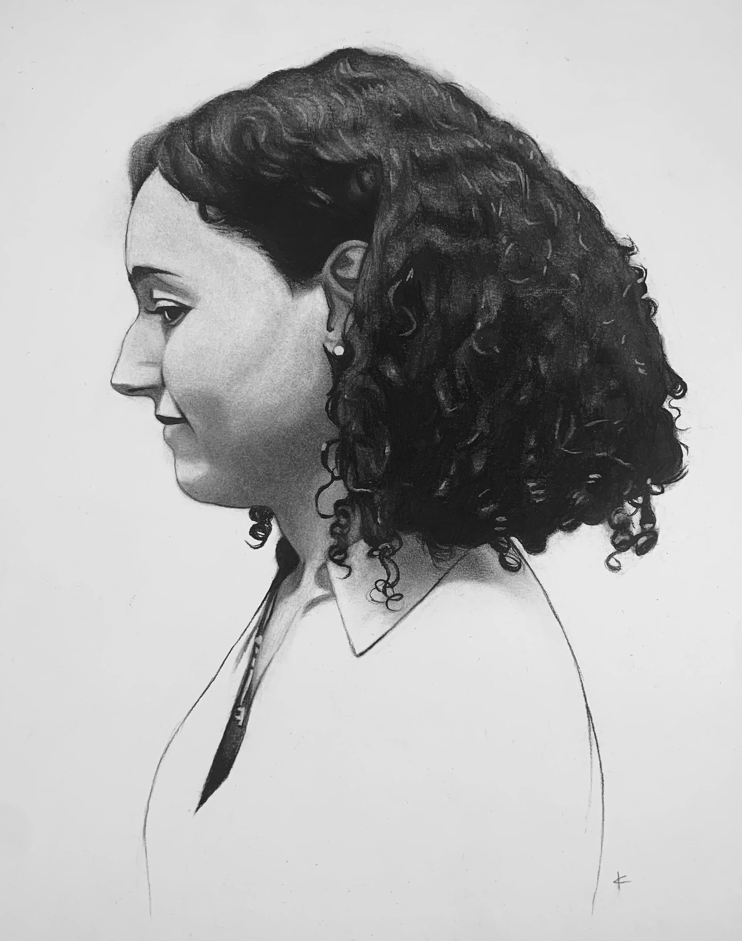 Black and white portrait of a woman in profile with curly hair, wearing earrings and a white top.