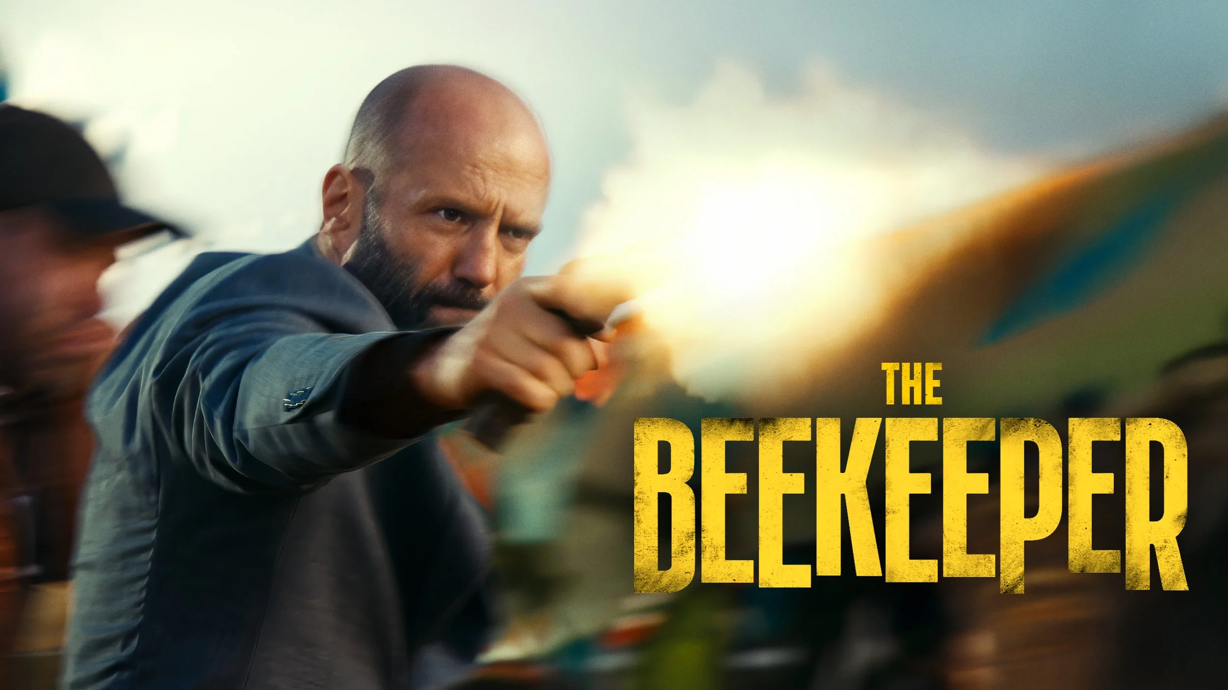 A man in a dark suit is aiming a gun with a serious expression. The background is blurred, and there are partially visible people. The text 'THE REDEEMED DELETER' is in bold yellow letters on the right side of the image.