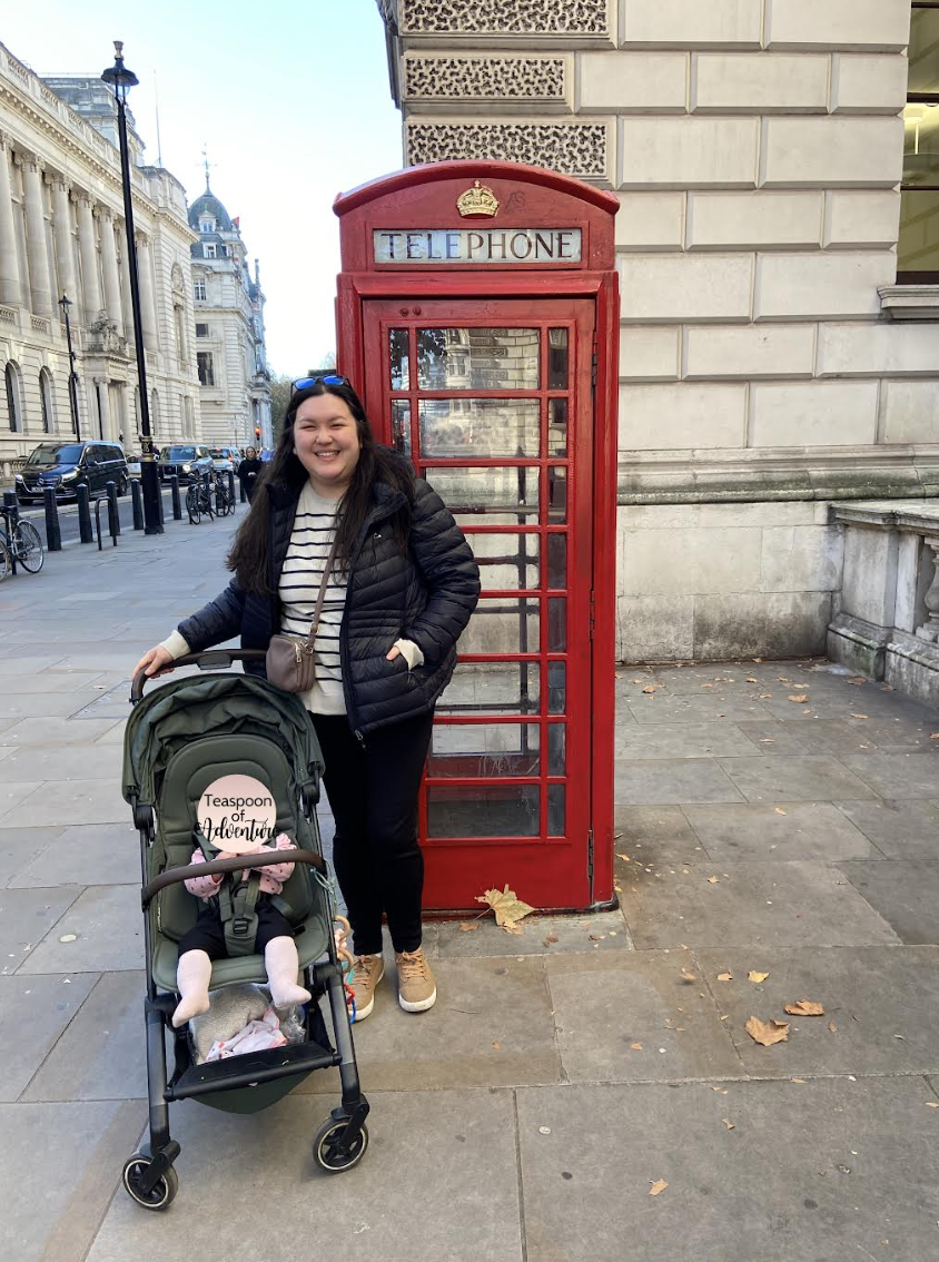 Riana and her baby in front of a phone booth