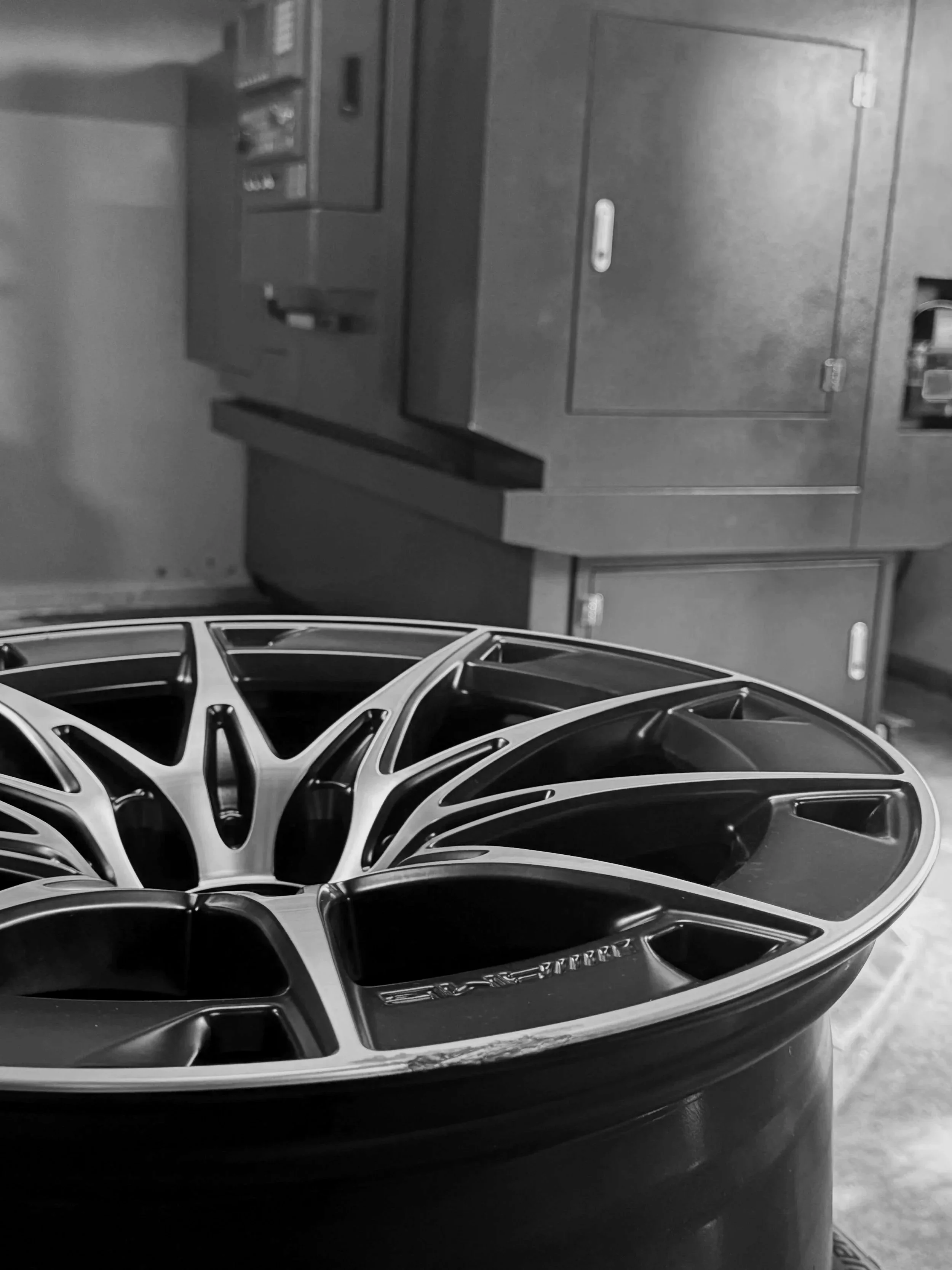 Ein schwarzer Autosportfelgen auf einem Flaschentank auf einem Boden, im Hintergrund metallene Schränke.