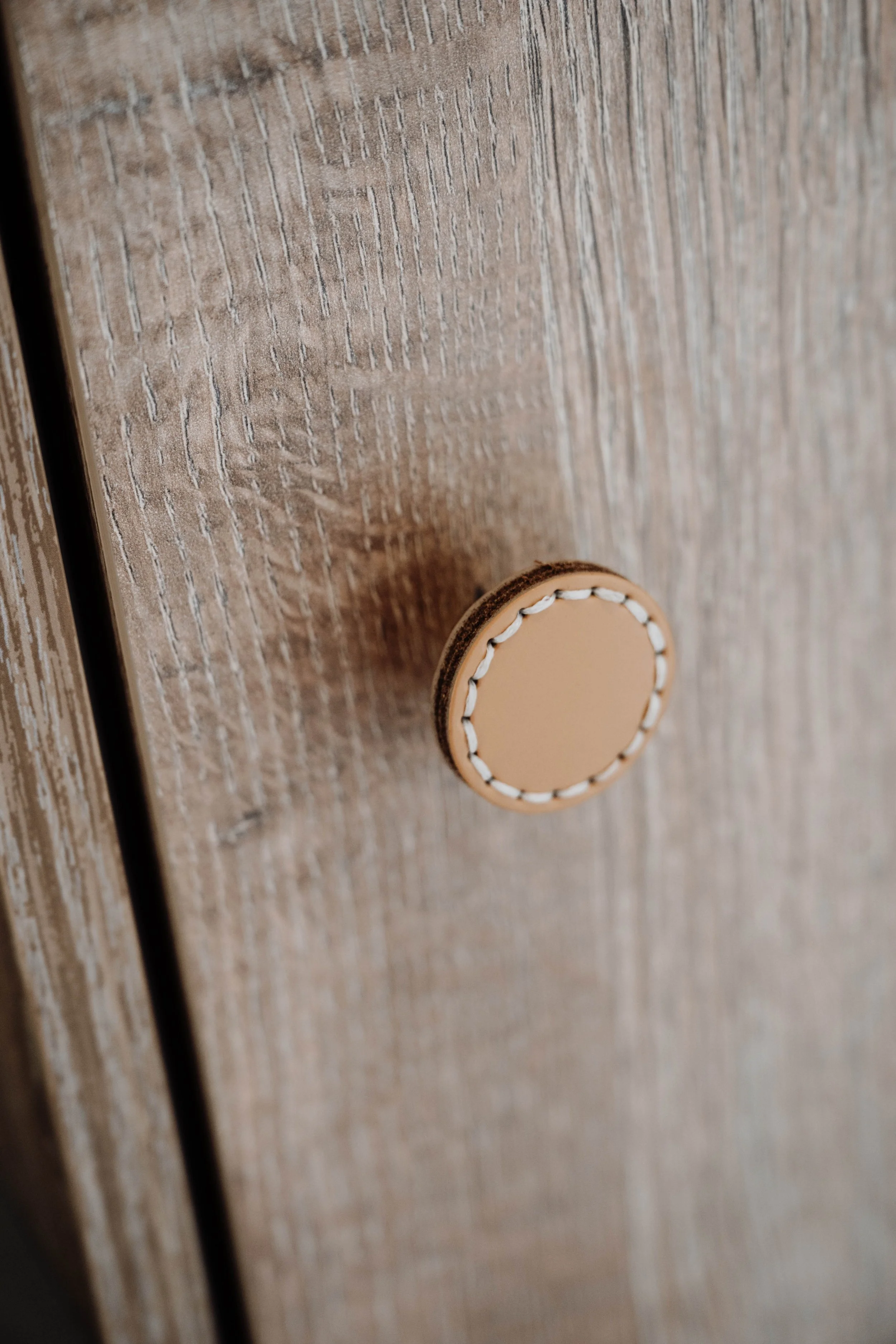 Close-up of a round beige button on a wooden surface.