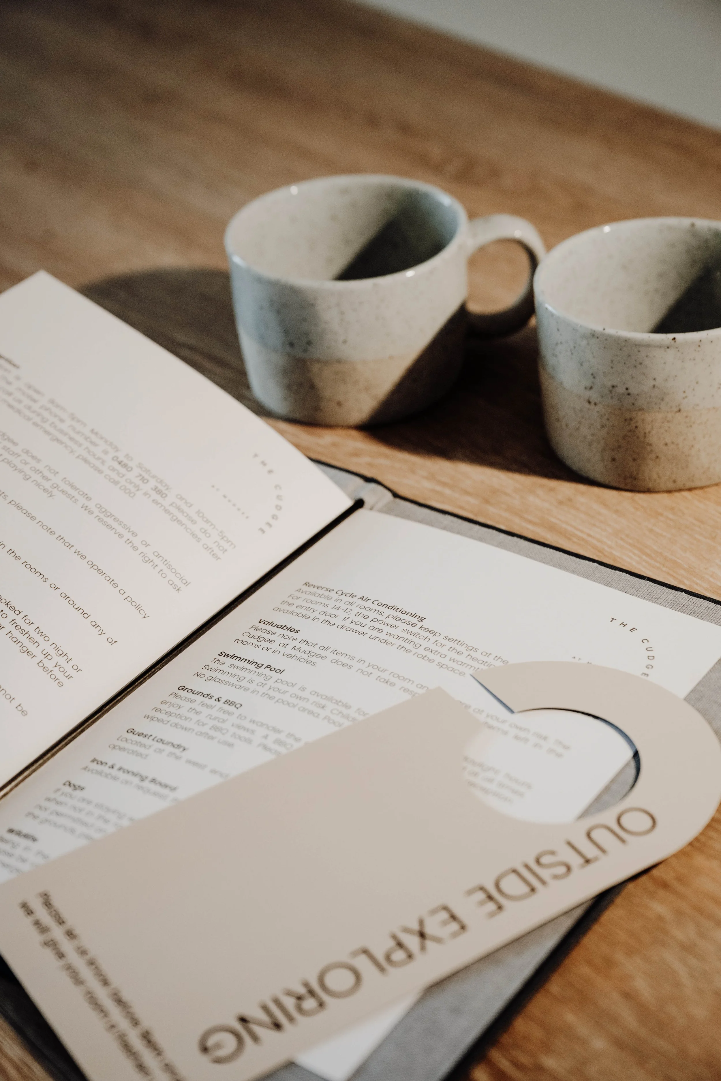 Two ceramic mugs and a menu on a wooden table.