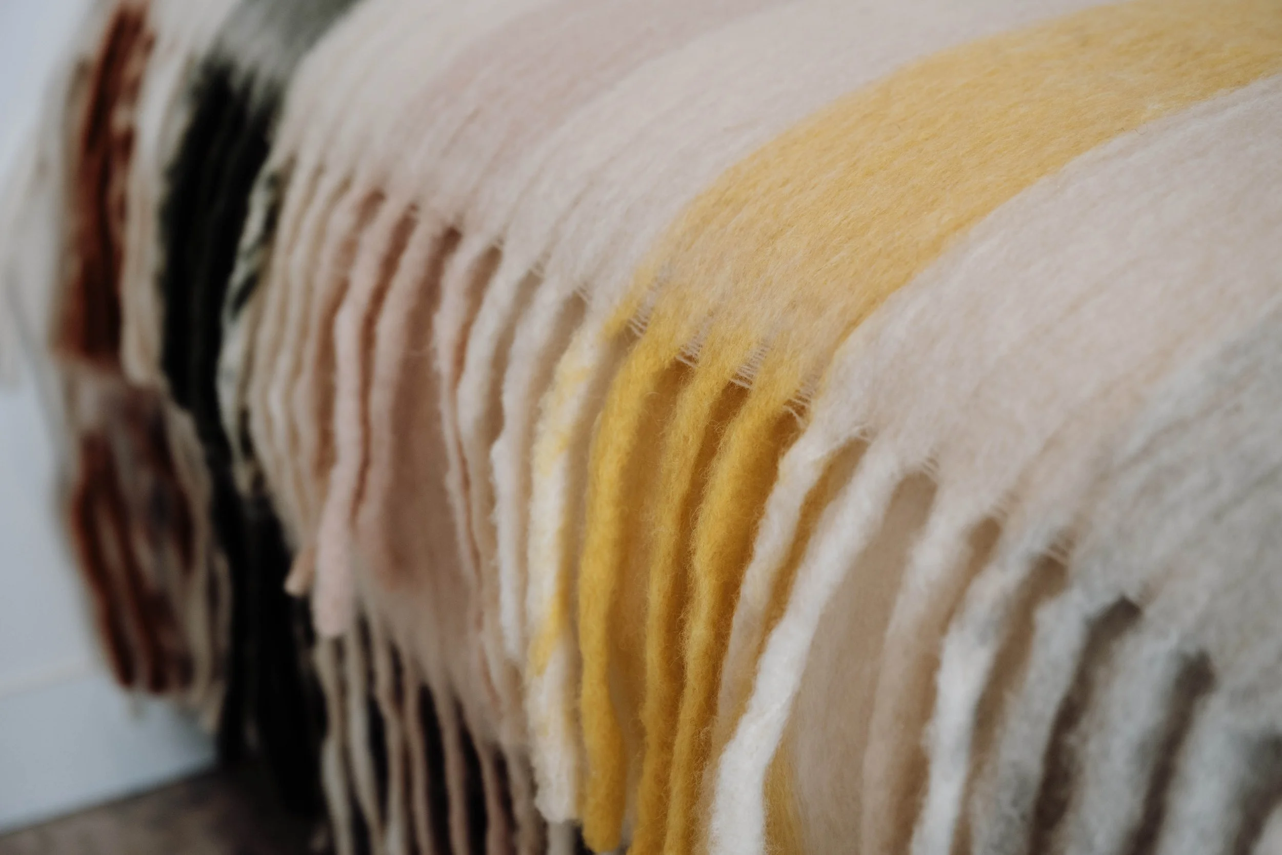 Close-up of rolled felt sheets in various colors, including black, pink, yellow, and white.