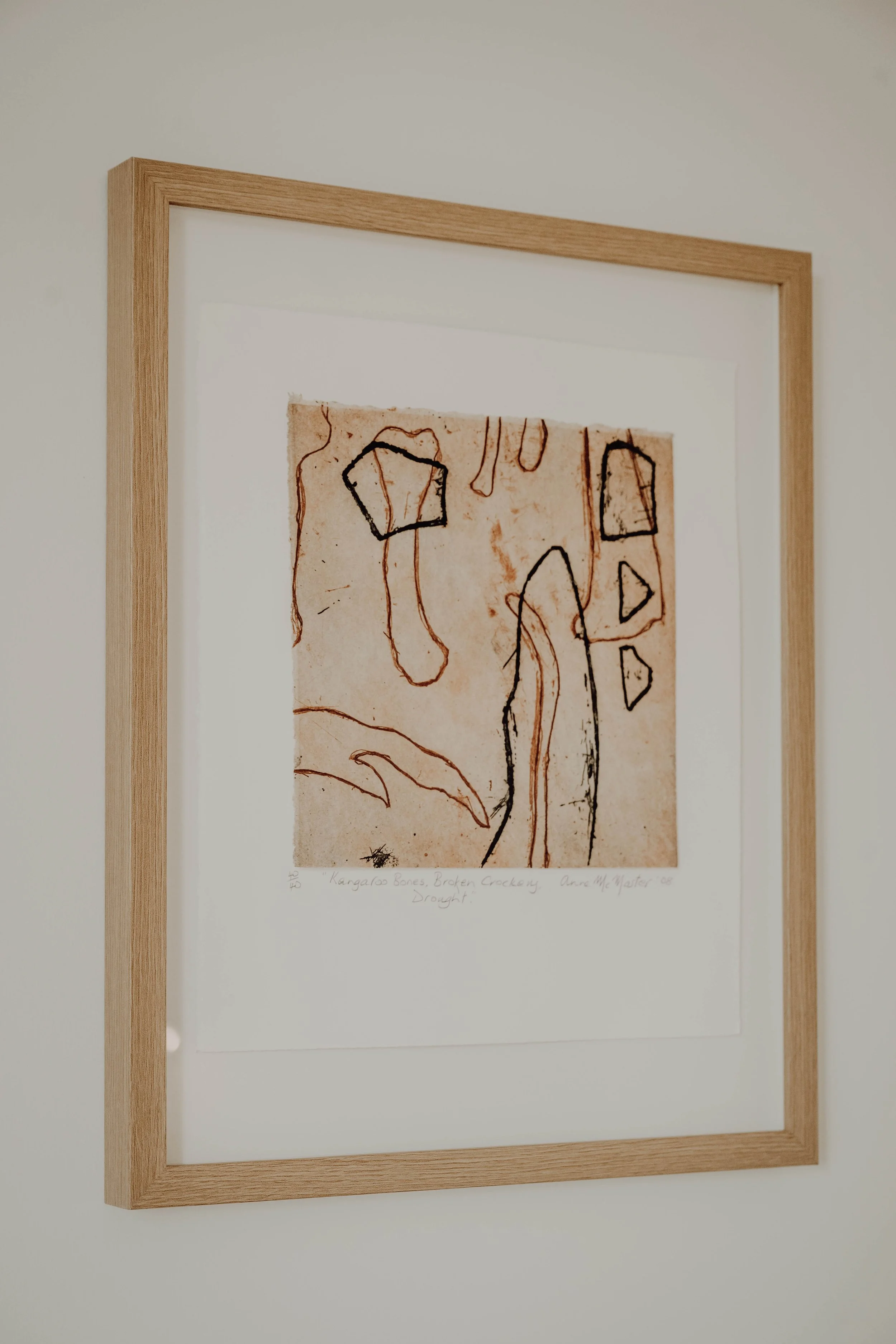 A framed piece of artwork featuring abstract, colorful line drawings on a textured background.