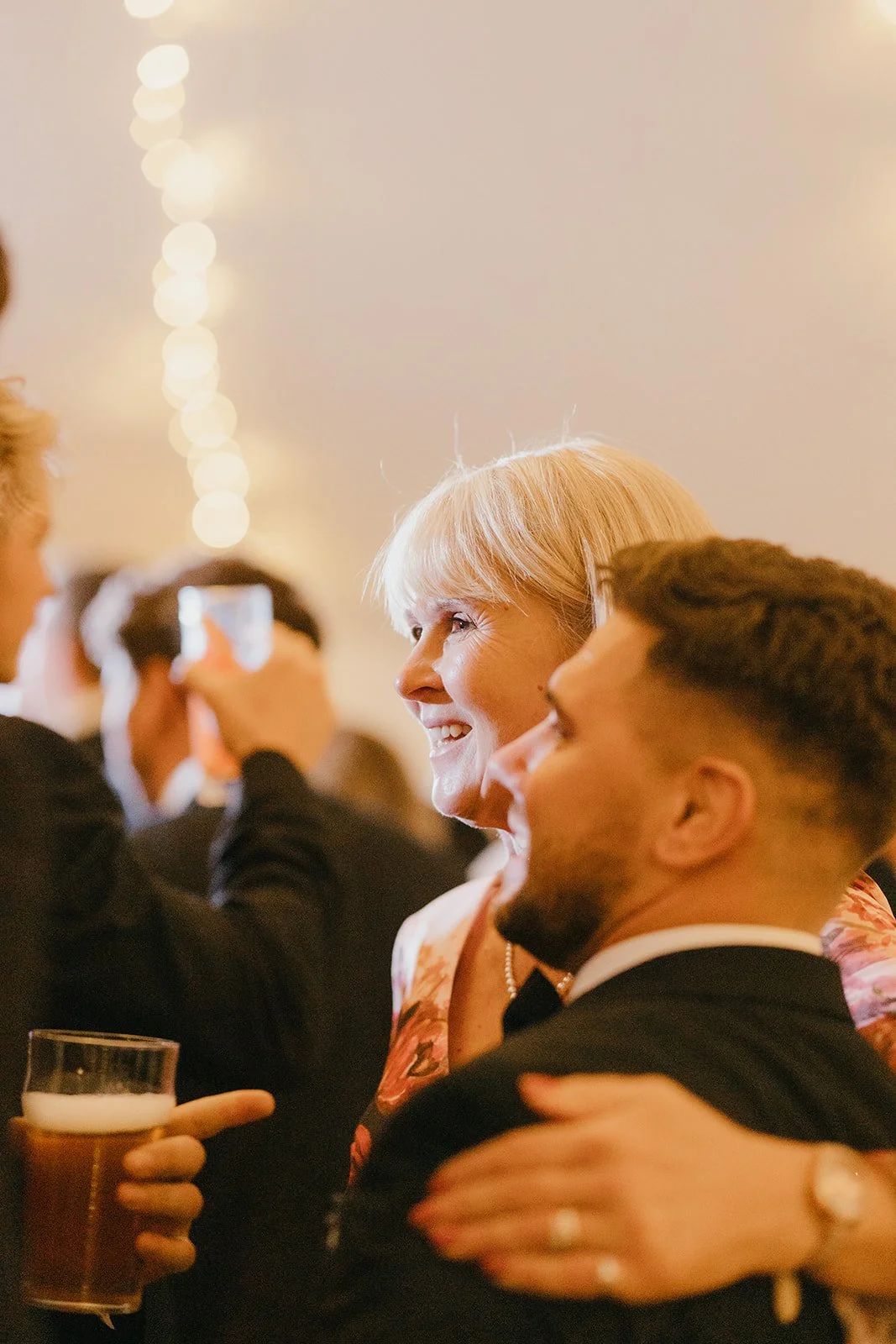 People celebrating at a social event, with a woman smiling and a man holding a drink.