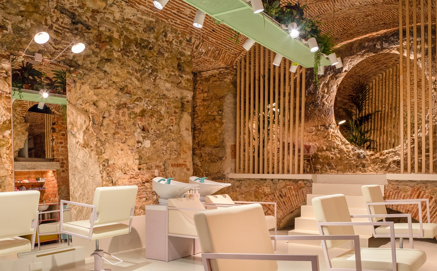 Hair salon with exposed brick walls, white chairs and plants