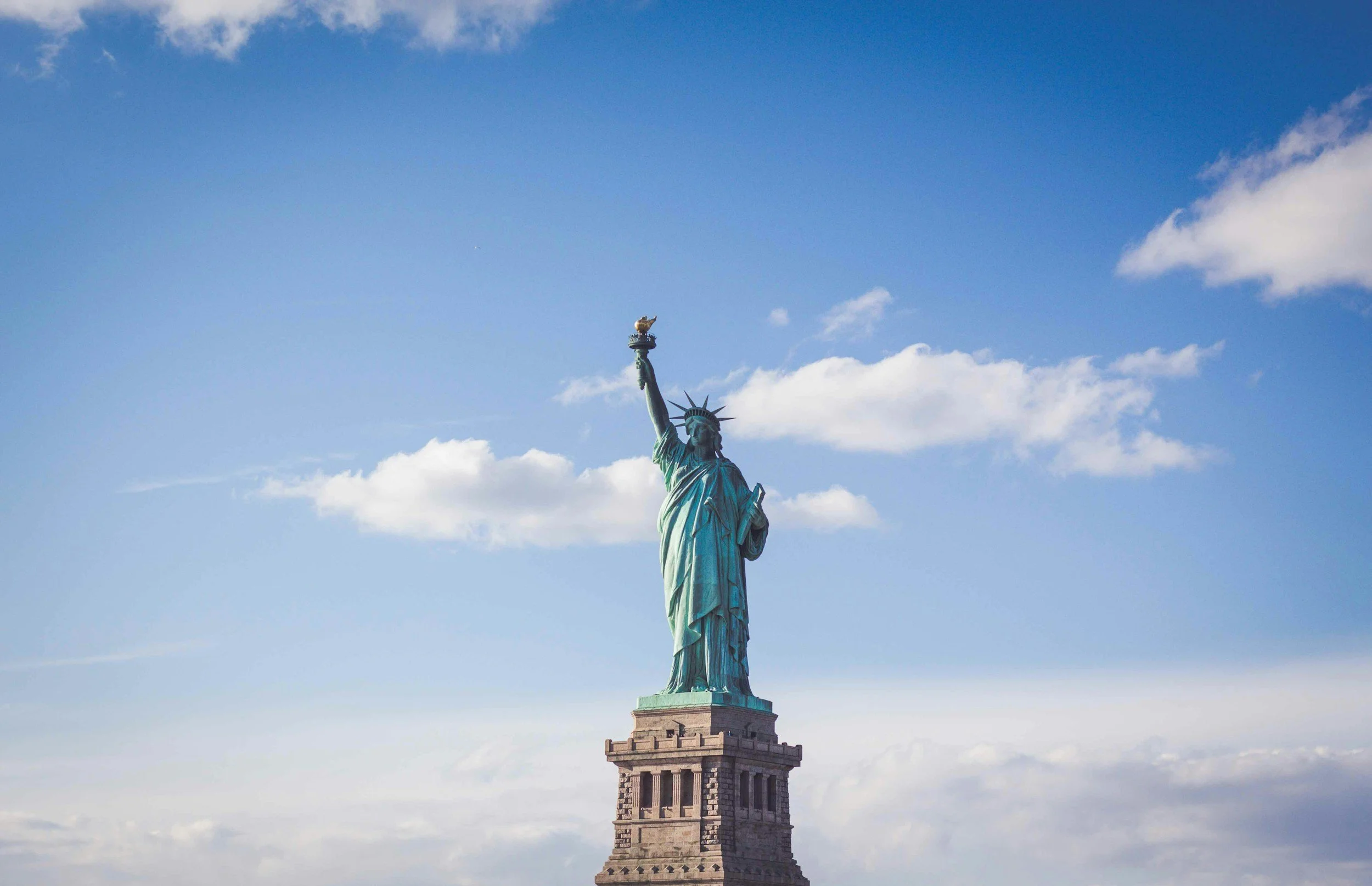 Statue of Liberty on a partly cloudy sky background.