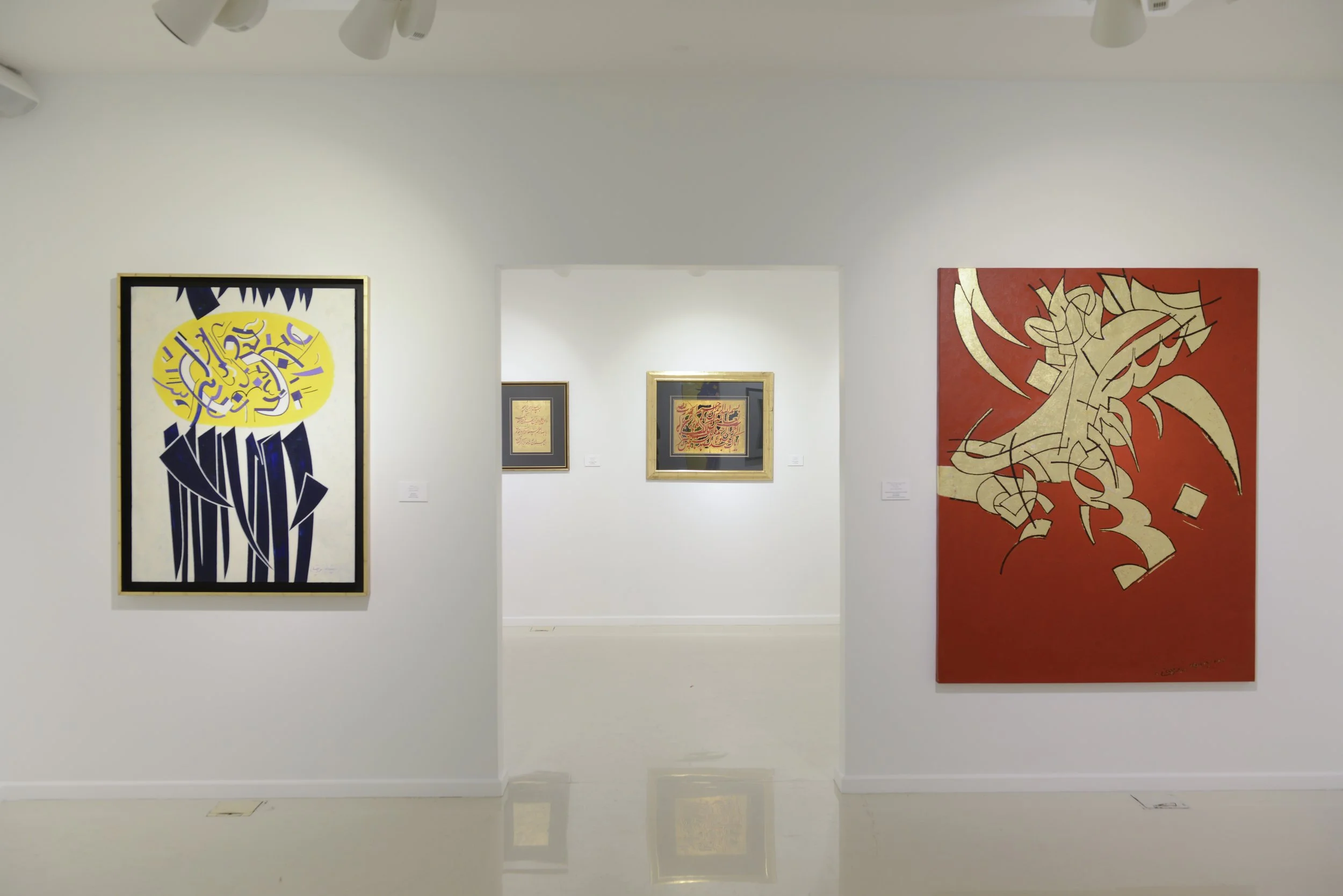 Art gallery with abstract paintings on white walls, featuring bold lines and colors, including black, yellow, red, and cream.