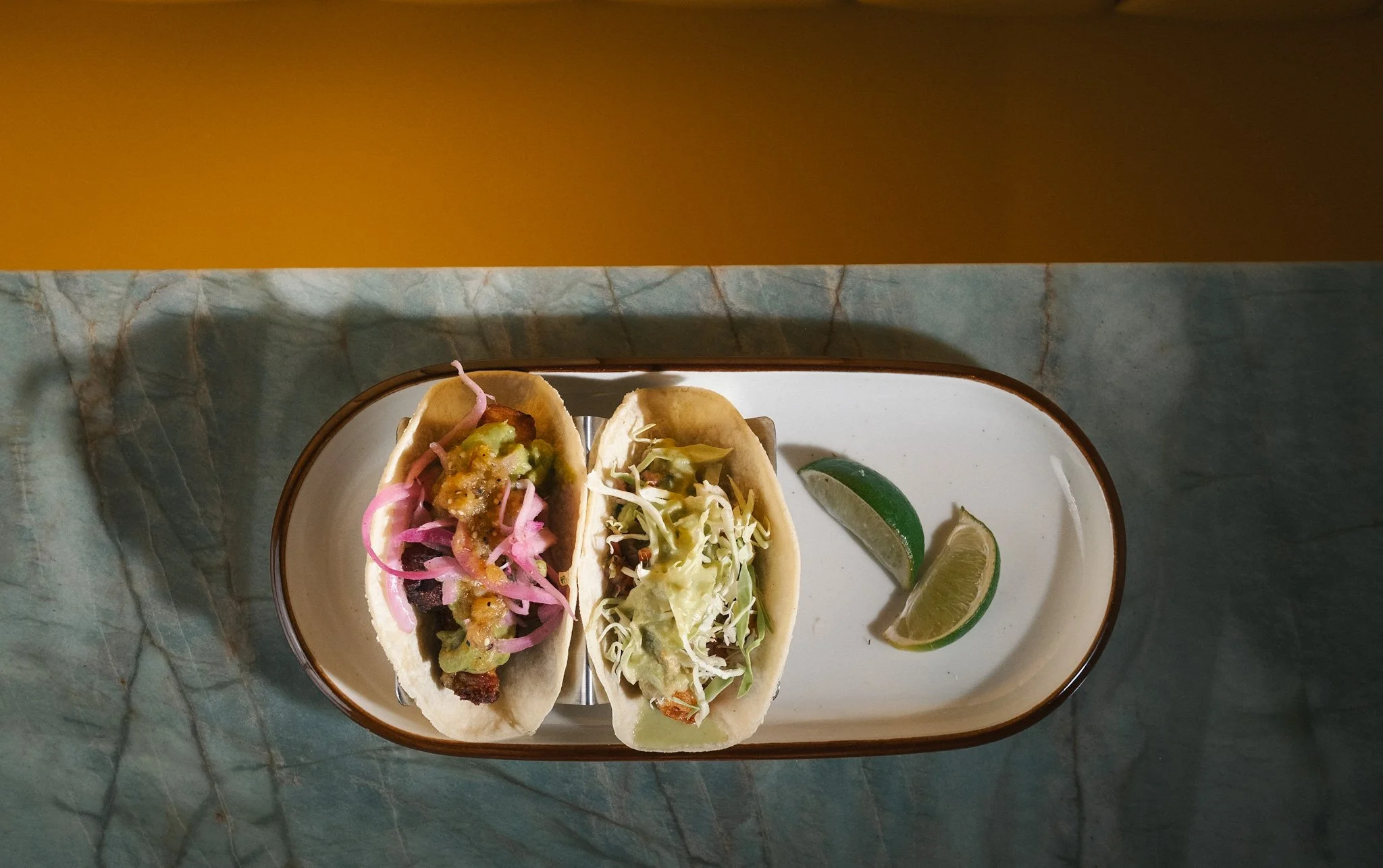 Fried fish taco with mango salsa and a chicharrón taco with guacamole at Gato Exótico in Cambridge, known for serving some of the best tacos in Cambridge.