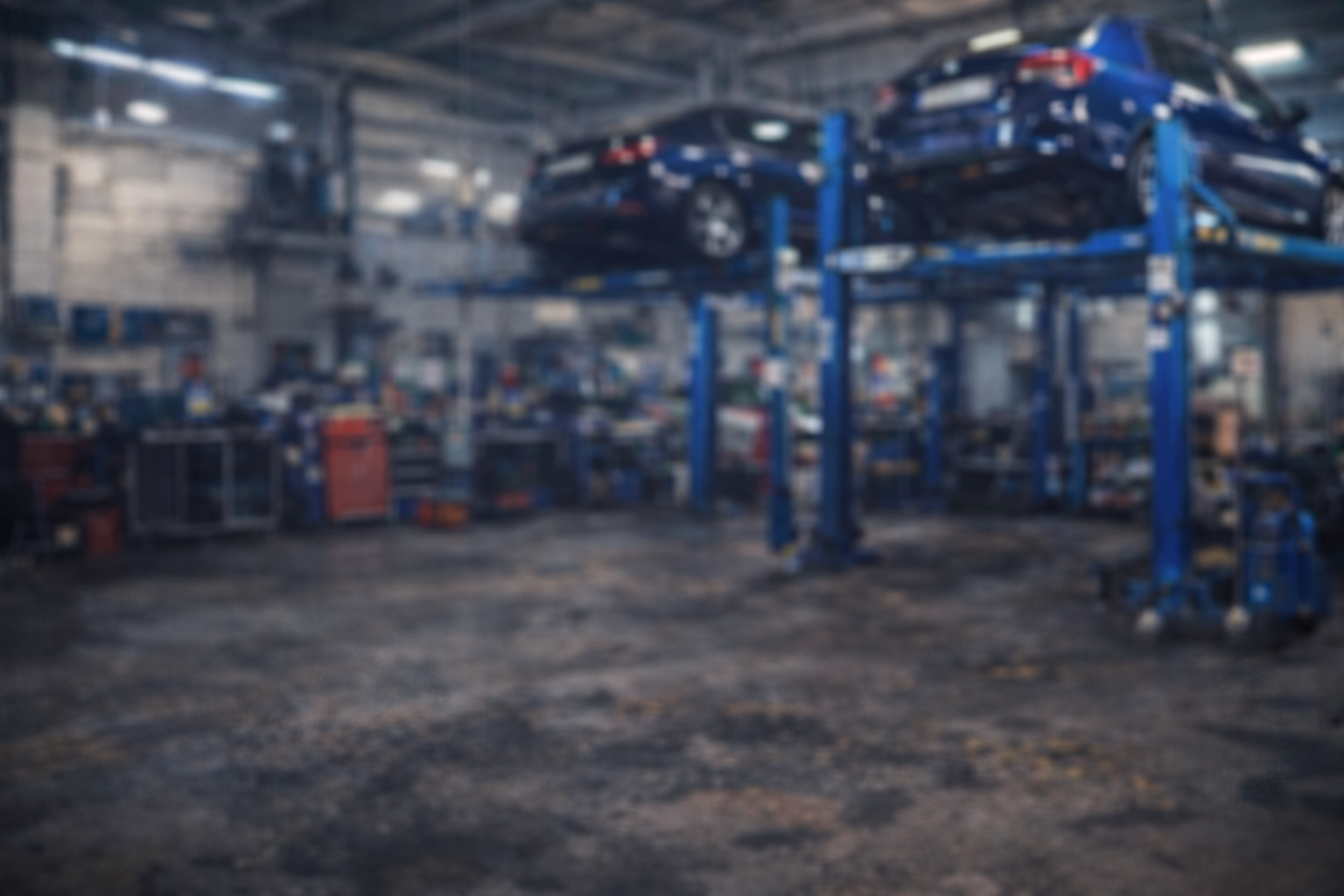 Een autoservicewerkplaats met twee auto bruggen waarop personen auto's staan