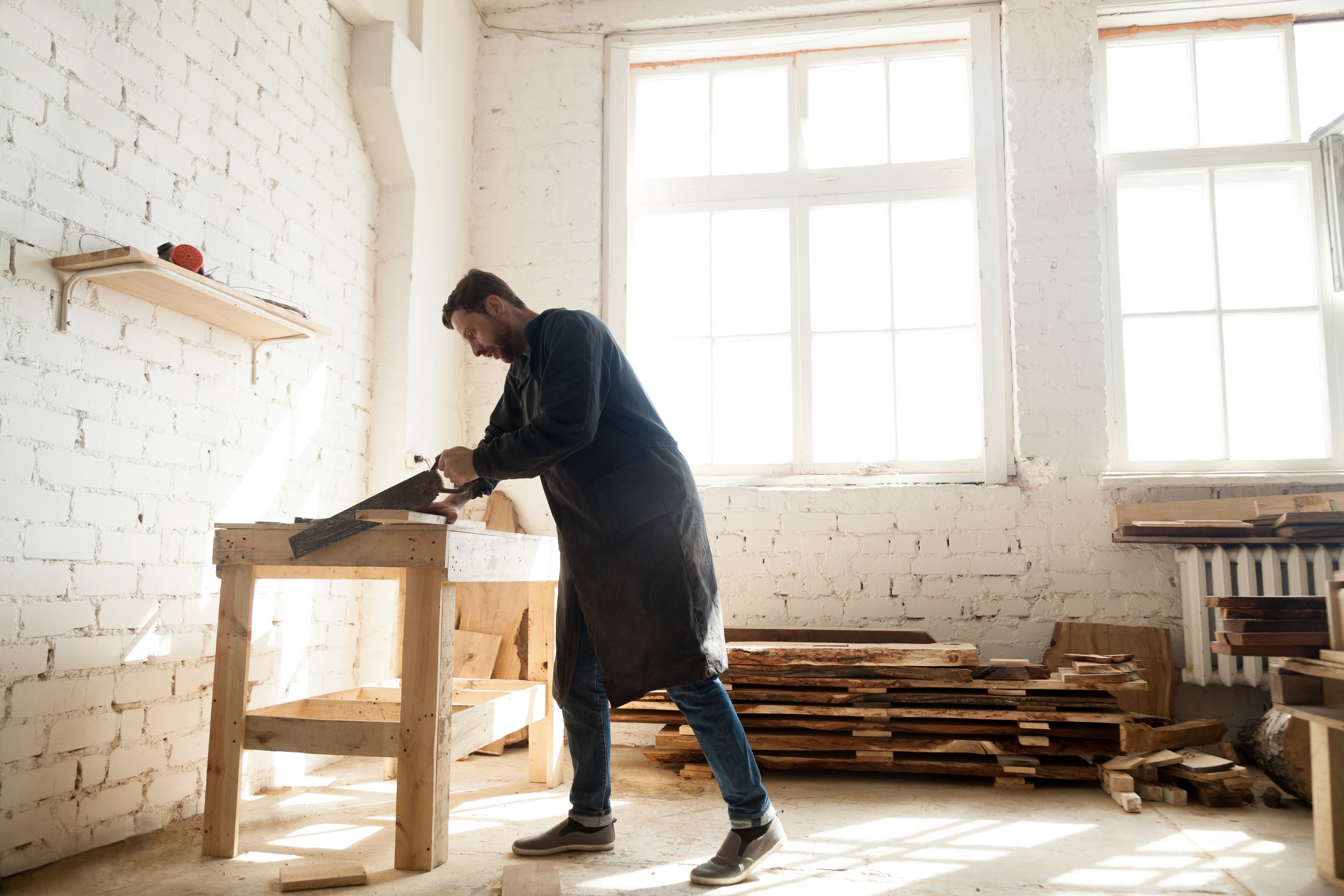 woodwork-construction-carpenter-using-handsaw-sawing-wooden-plank.jpg