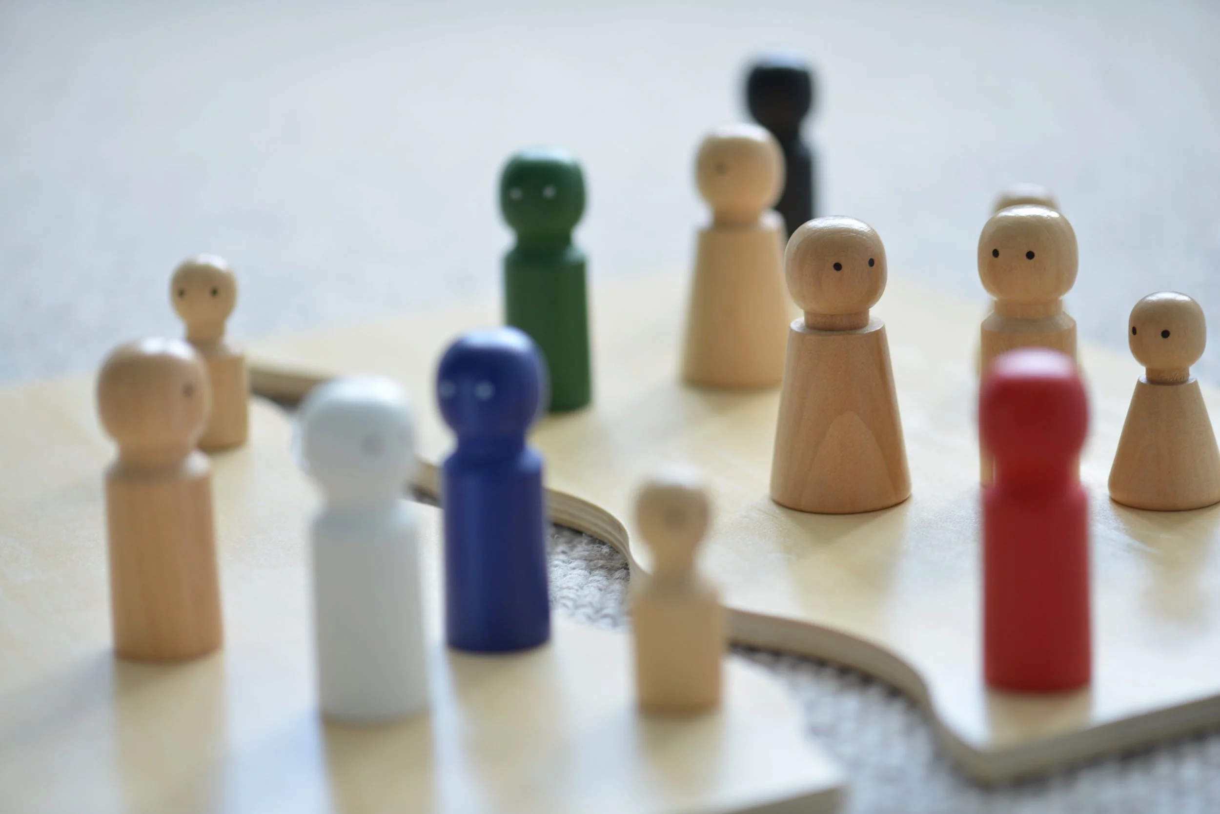 Bunte kleine Holzfiguren auf einer Spieltafel, die eine Landkarte darstellt.