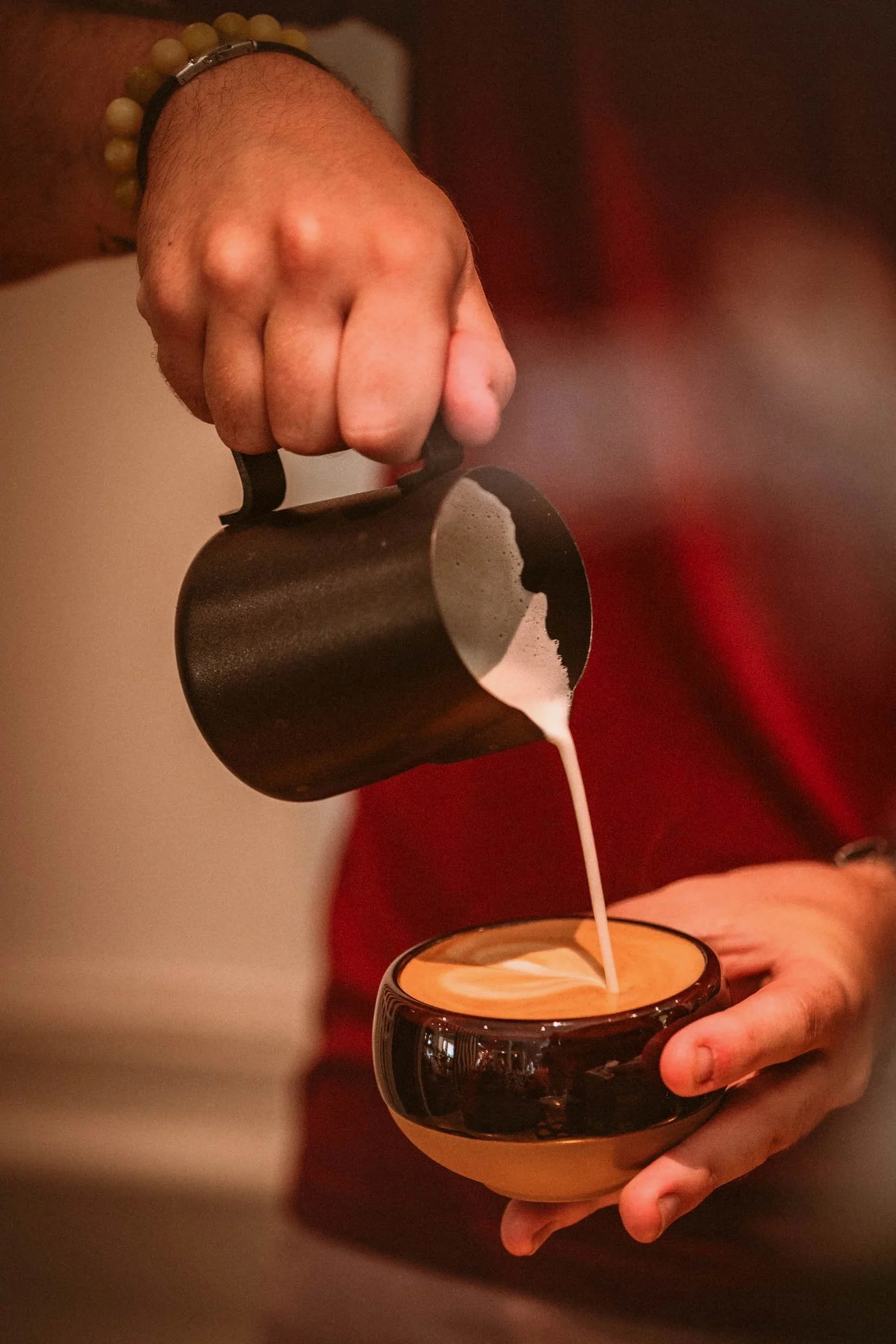 Une personne verse de la crème de café chaud dans une tasse