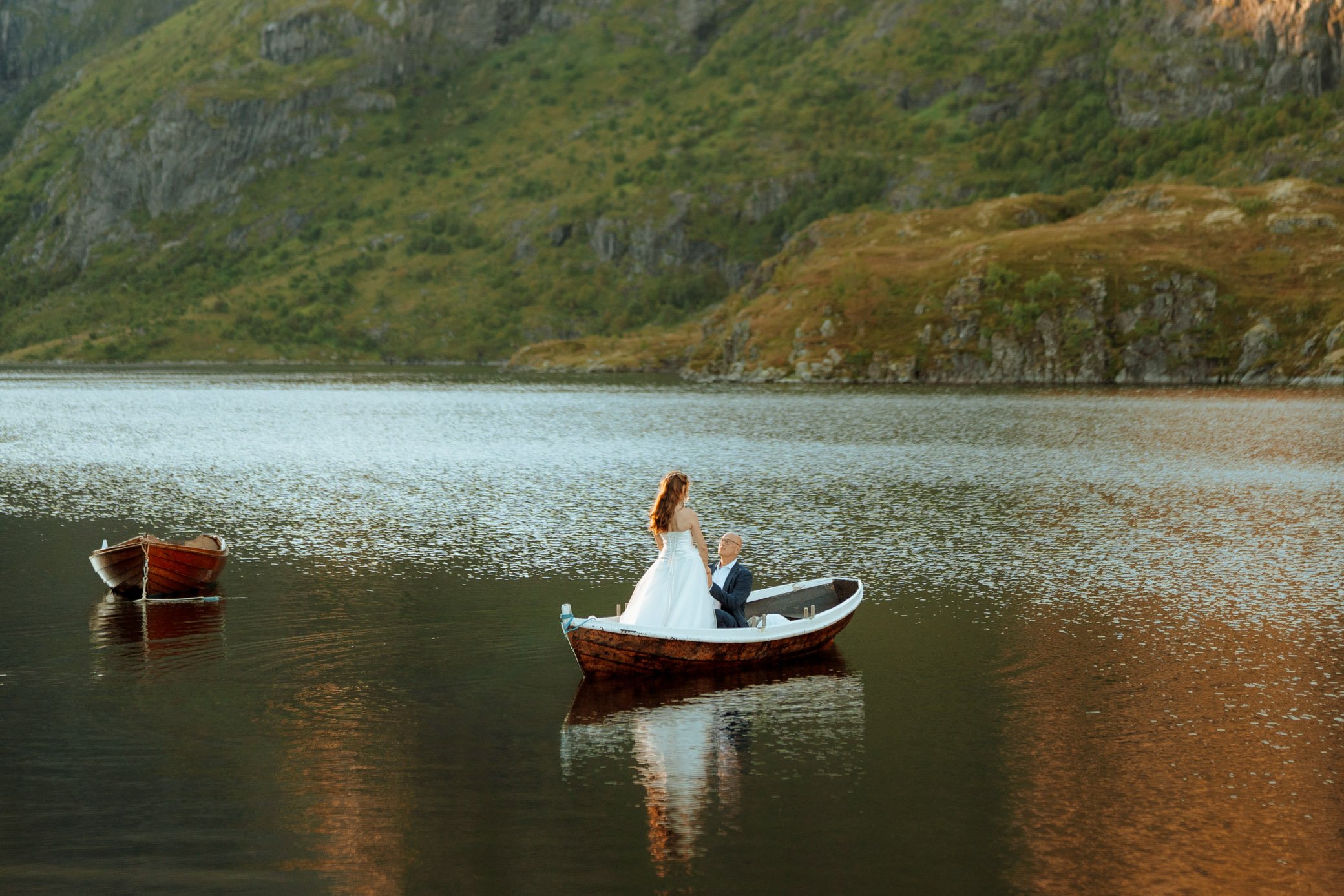Couple exchanging vows on a small boat on a mountain lake during elopement in Lofoten Norway