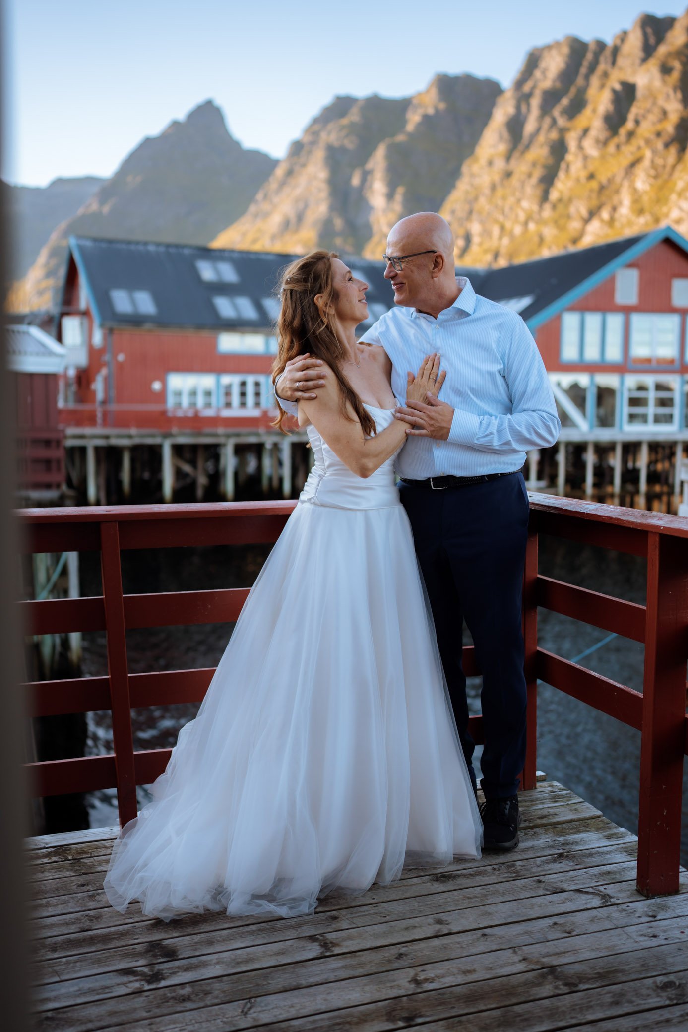 Couple on terrace of traditional rorbuer in Lofoten with mountain views