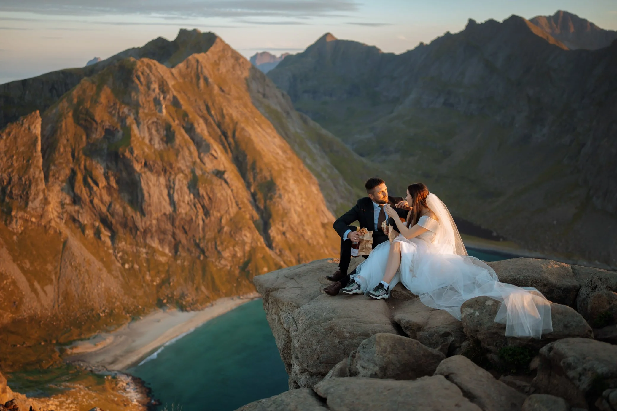 Couple eating cinnamon rolls on mountain in Lofoten 