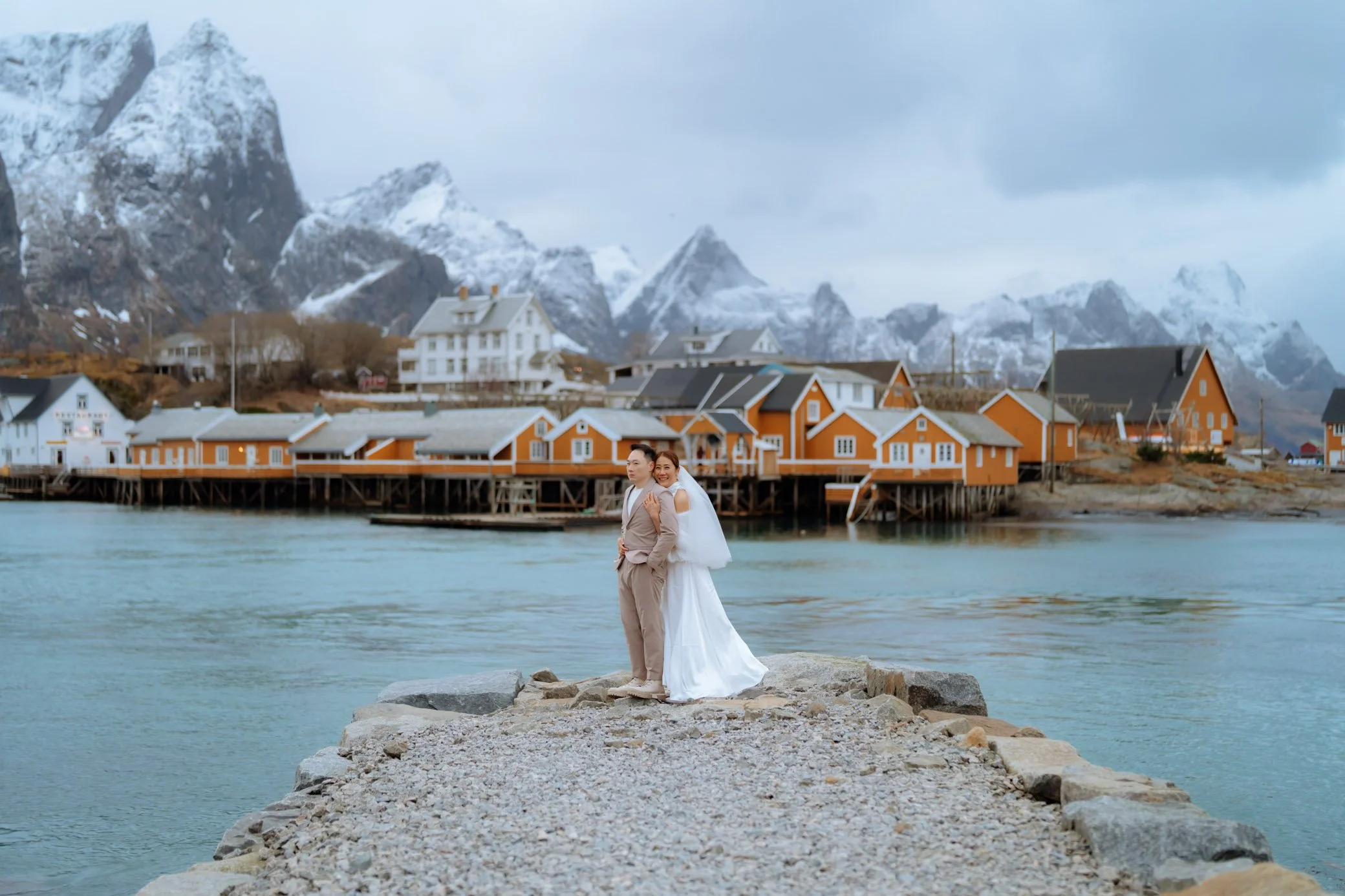 Bride and groom exchanging vows in Sakrisøy Lofoten with famous yellow rorbuer cabins behind them