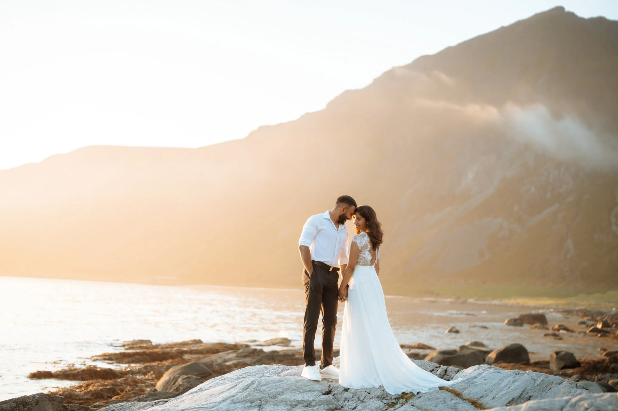 Couple standing on mountain viewpoint in Flakstad during intimate Lofoten elopement with sea views