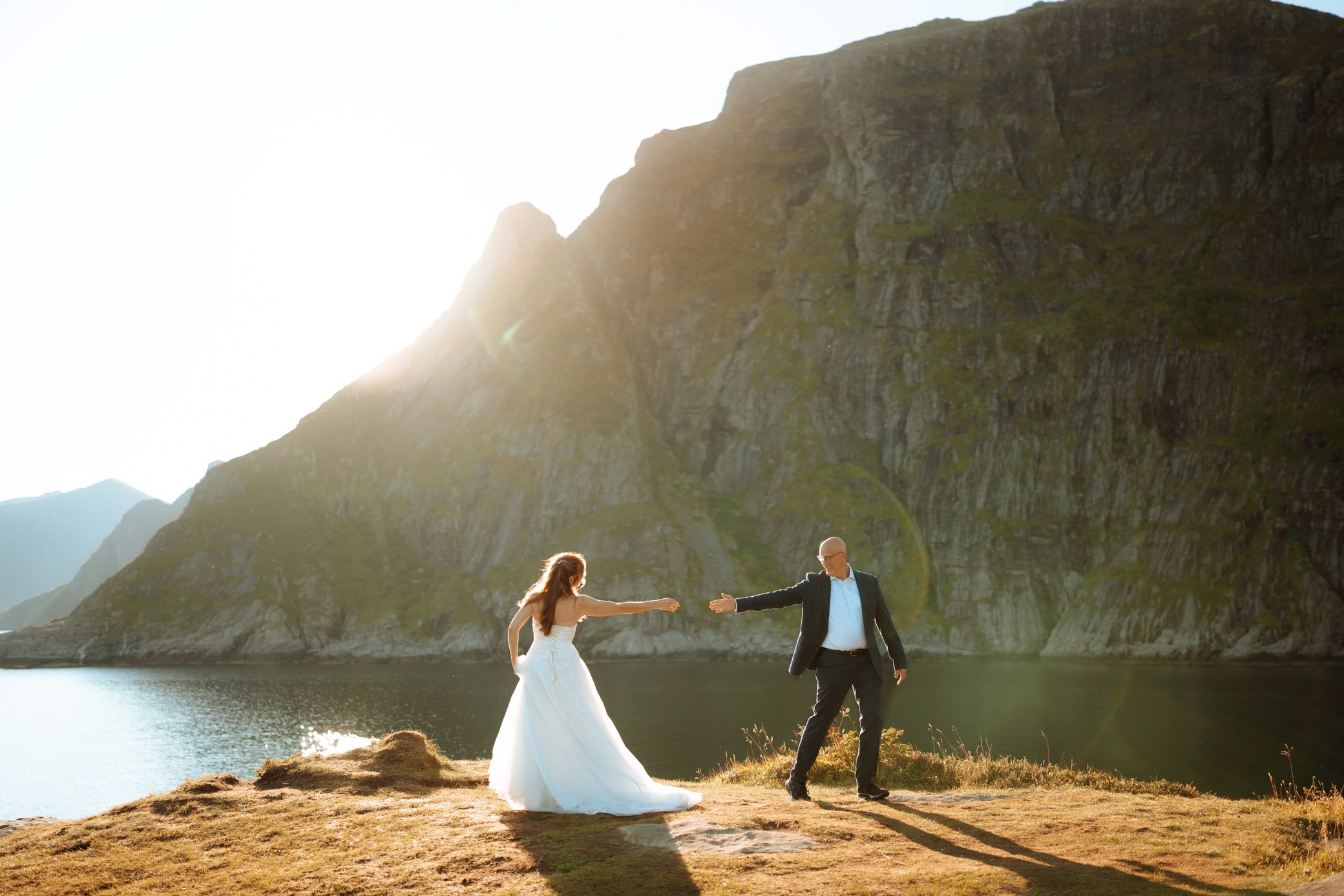 Couple standing in Lofoten mountains with warm sunset light during elopement