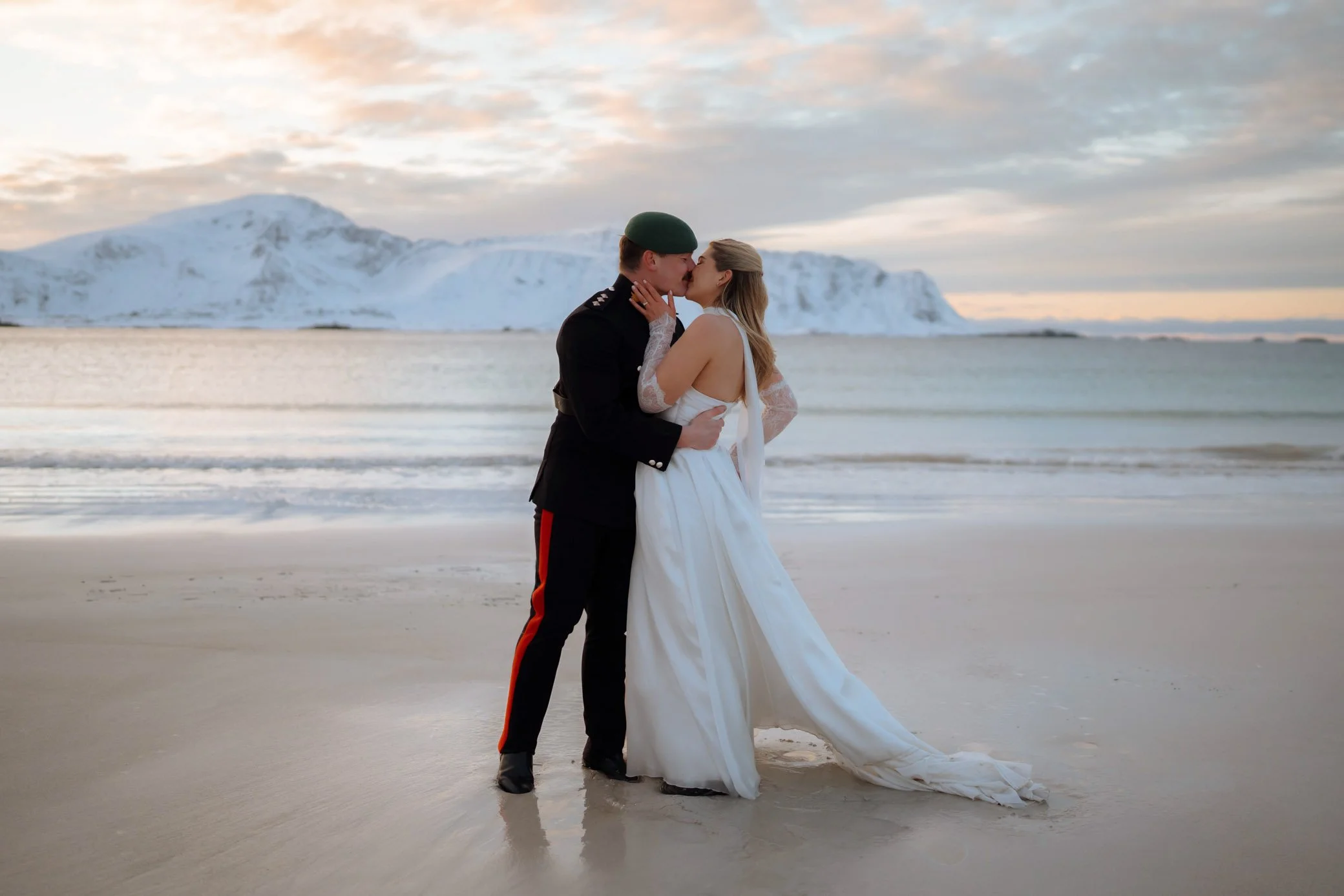 Bride and groom on Ramberg Beach during elopement in Lofoten surrounded by white sand and Arctic mountains