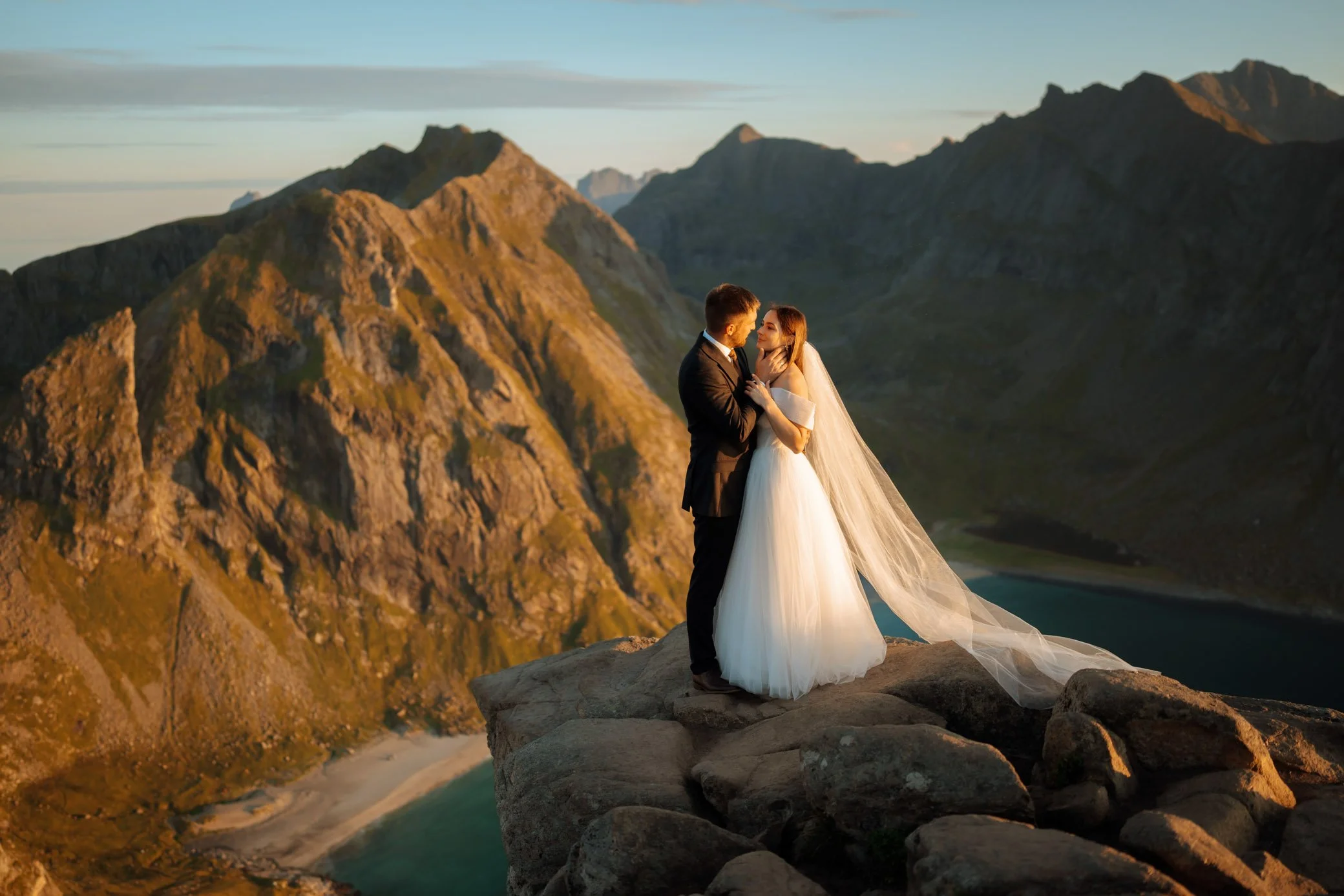 Couple on top of Ryten mountain during Lofoten elopement overlooking Kvalvika Beach in Norway