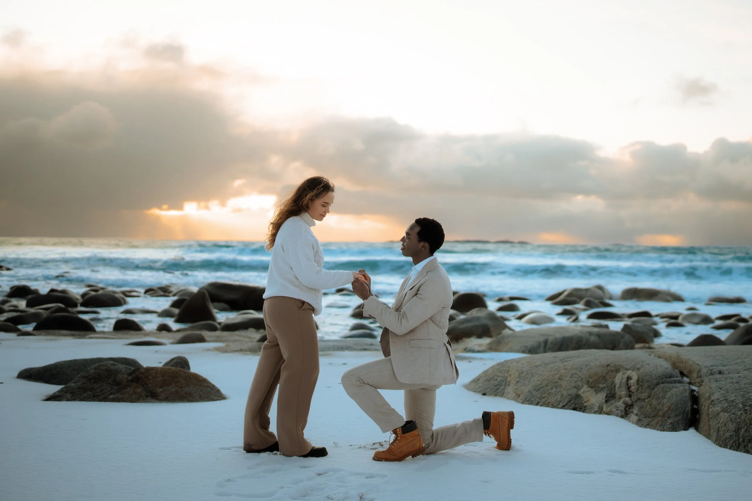 Surprise proposal in Lofoten, Norway — groom-to-be kneeling as partner says yes, captured by a local Lofoten engagement photographer with mountains and fjord backdrop.