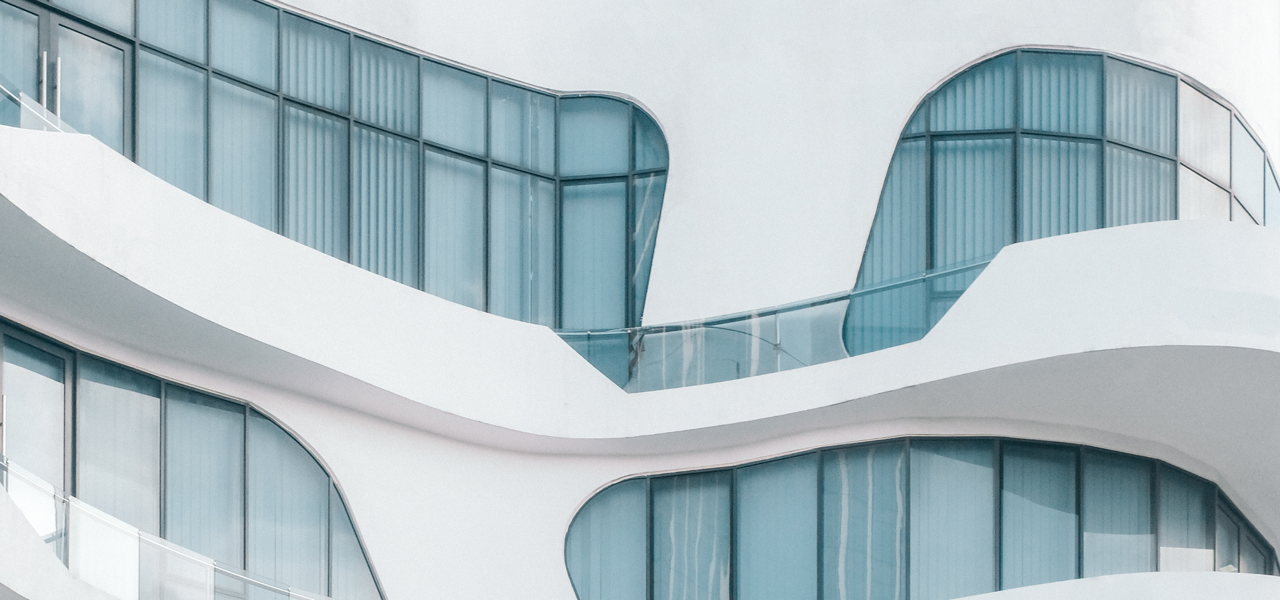 Modern building with white curved surfaces and large glass windows.