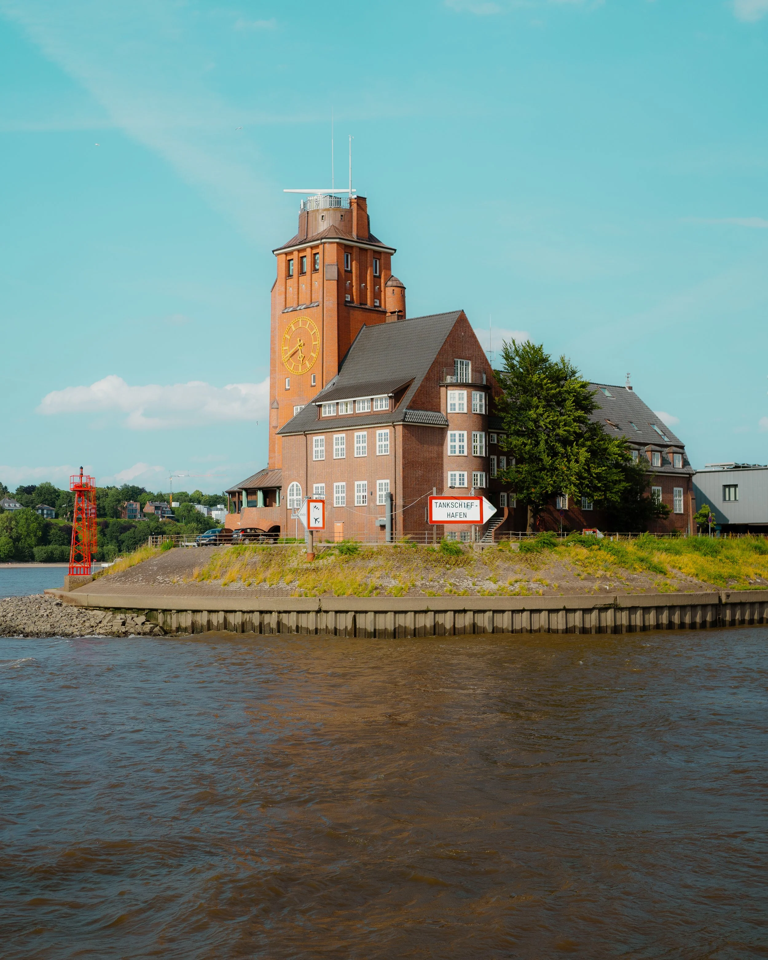 A large brick building with a clock tower on a waterfront.