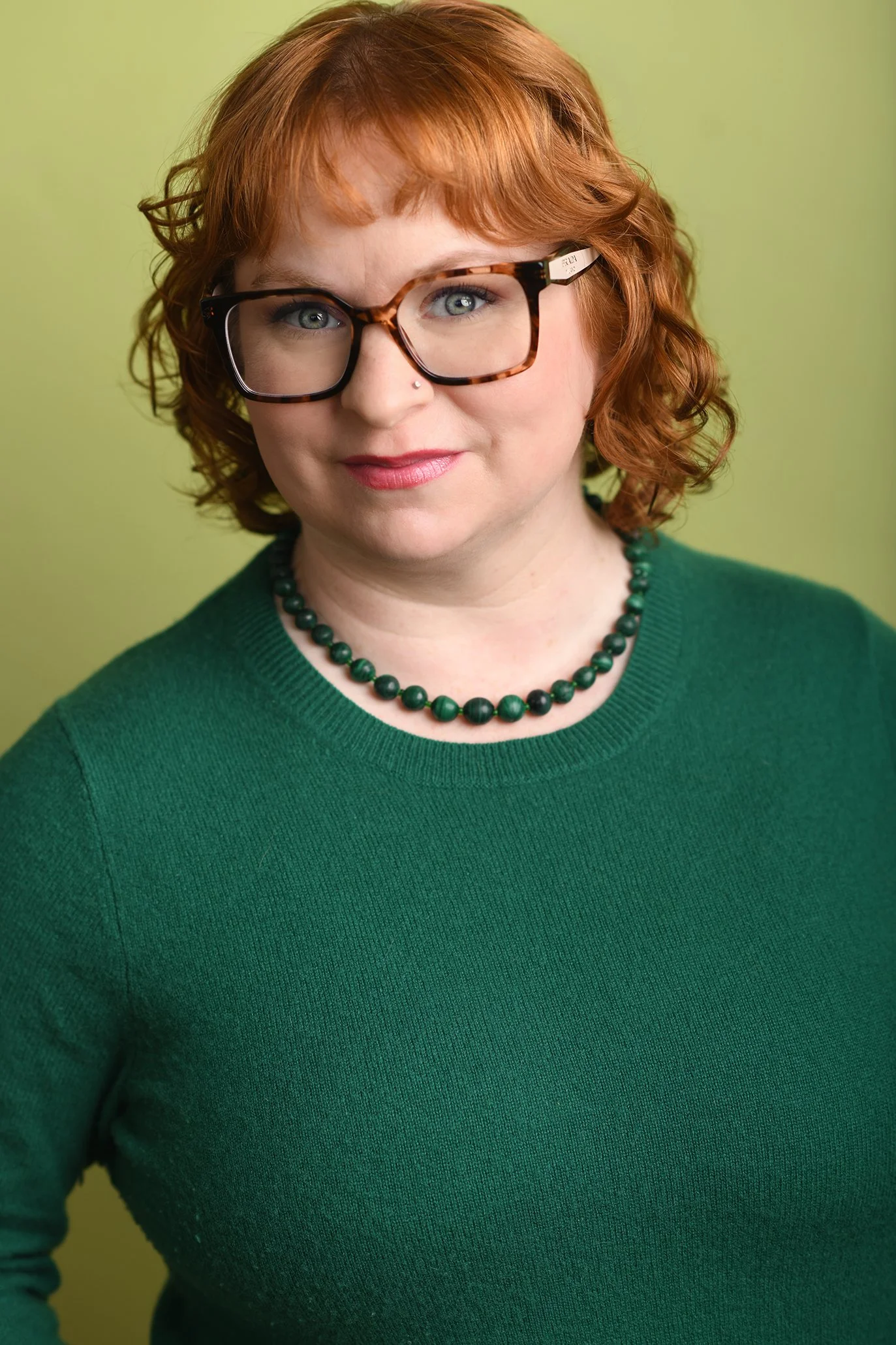 Vertical headshot of Alexandra Fallgren, she gazes at the camera with a serious expression