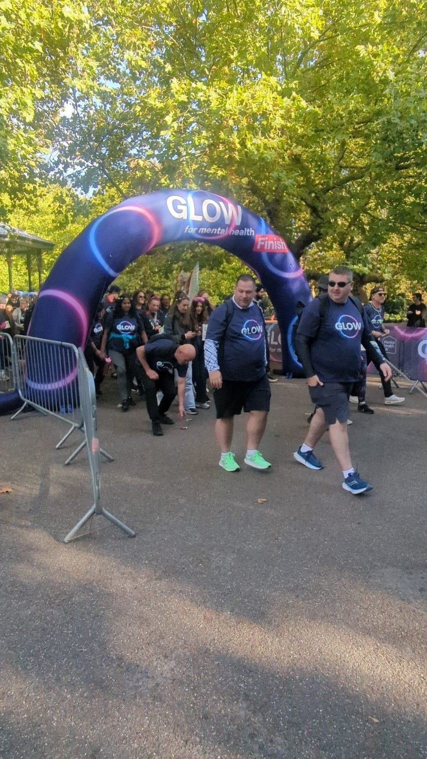 Walkers crossing the Glow for mental health finish line on a sunny day.