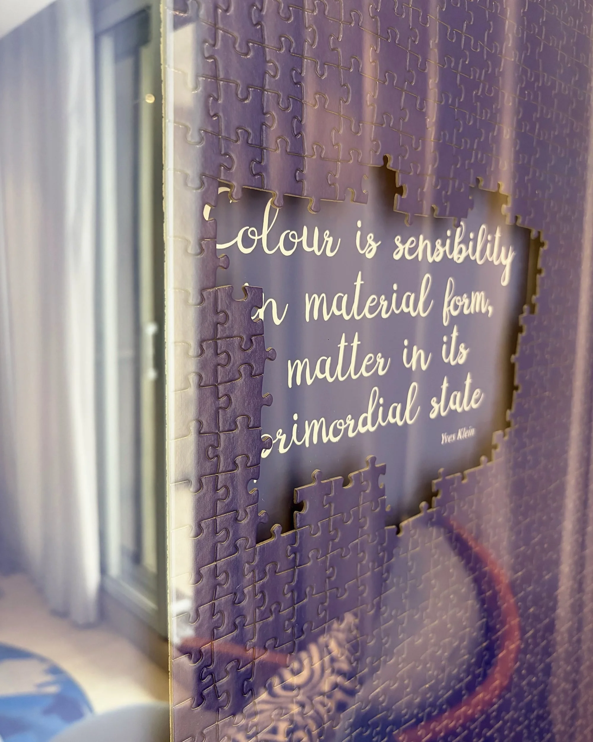 Purple jigsaw wall art with a Yves Klein quote revealed in the centre