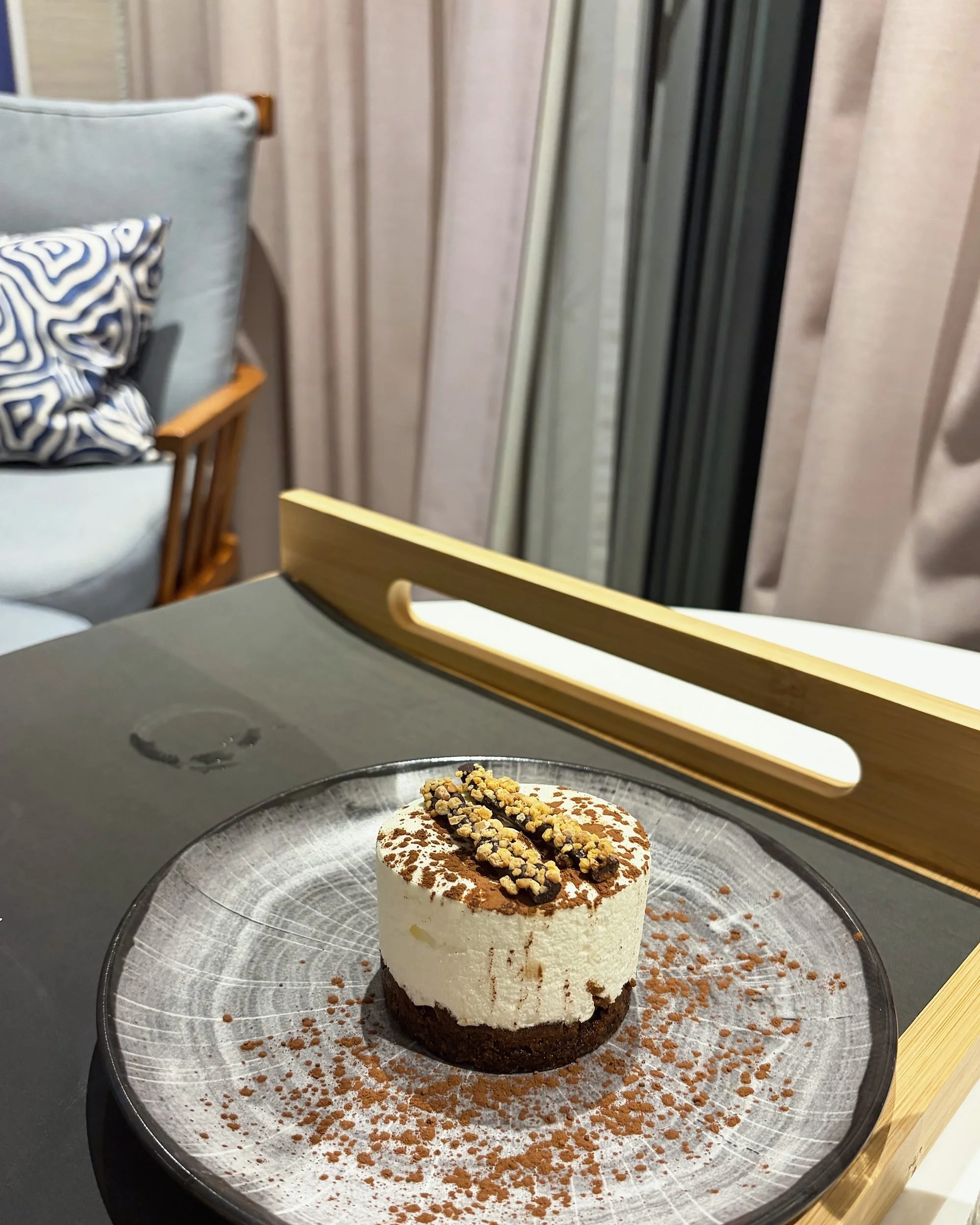 Small chocolate and cream dessert on a patterned plate on a room-service tray