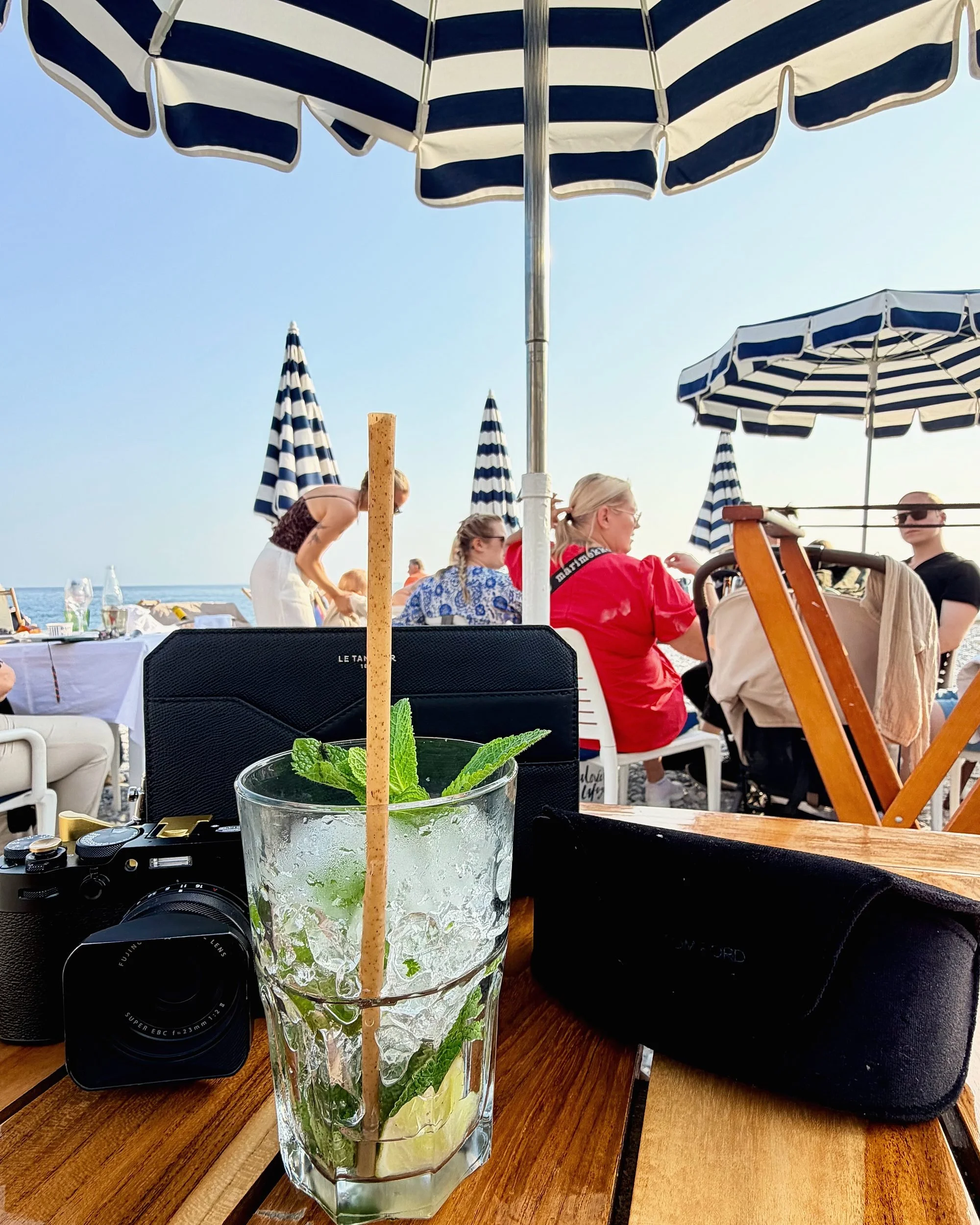 Mint cocktail on a beach-club table under navy and white striped parasols