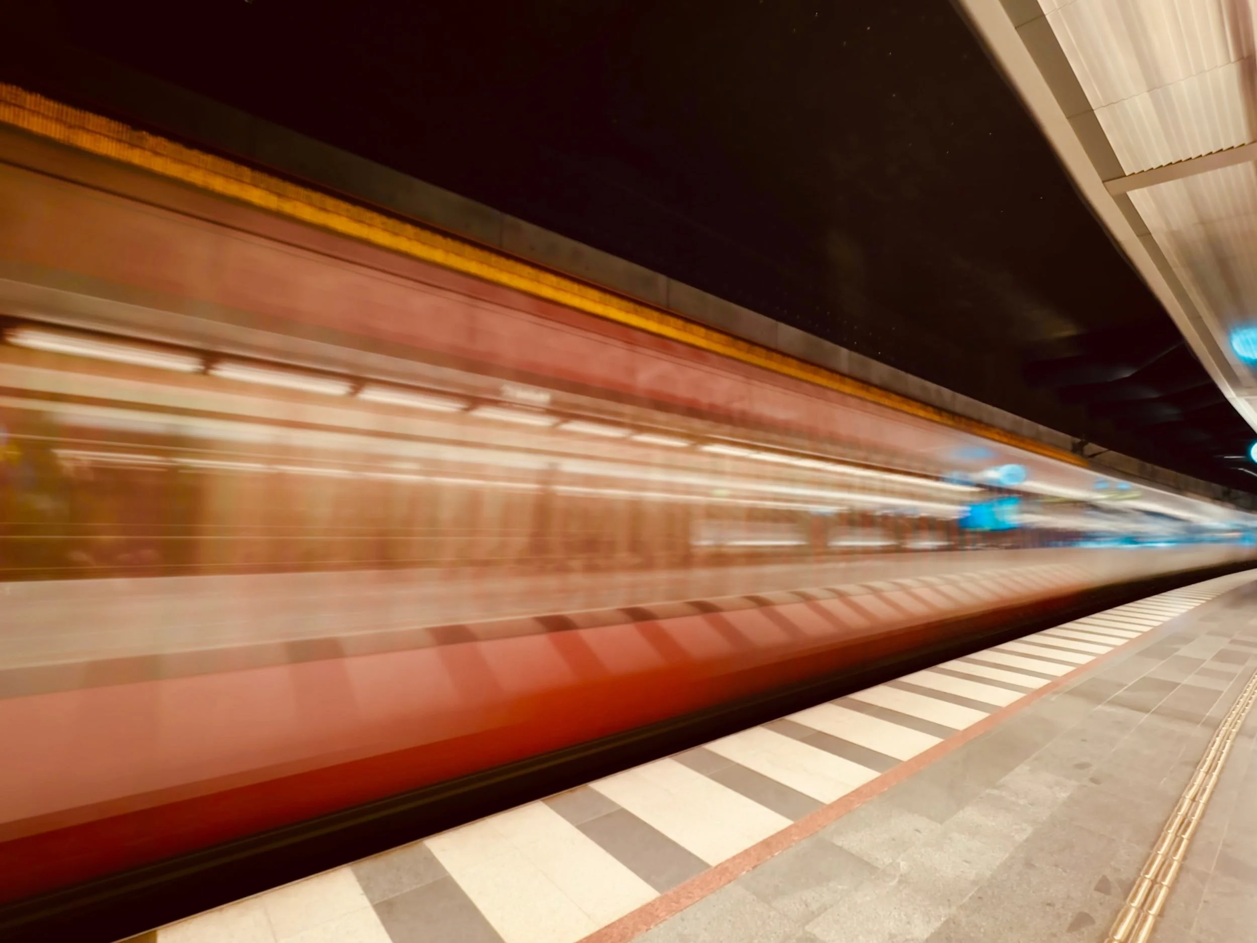 A Copenhagen Metro train in motion blur at a platform.