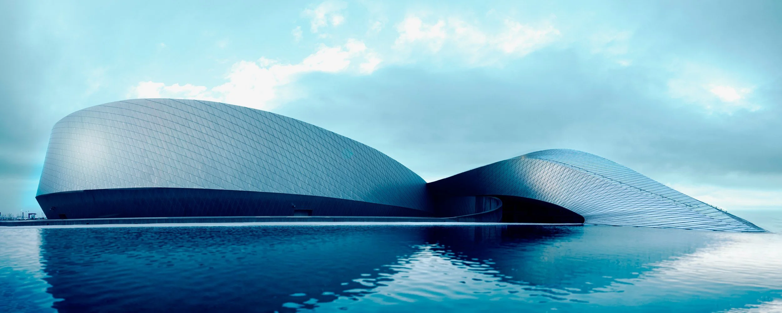 Blue Planet aquarium in Copenhagen, its silver curved façade reflected in the water.