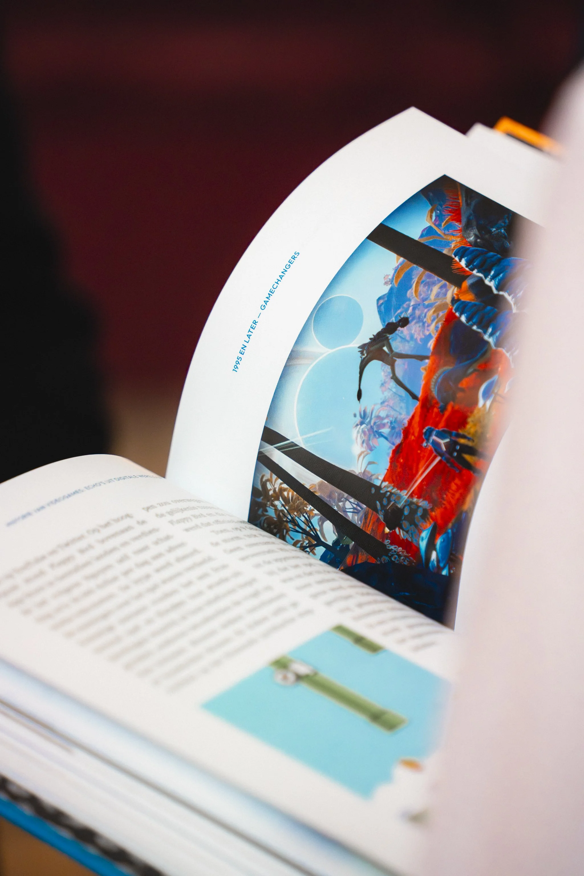 Open magazine with colorful images, including a surreal scene with a person in a blue and orange outfit, and text on the page that reads '1995 EN LATER - GAMECHANGERS'.