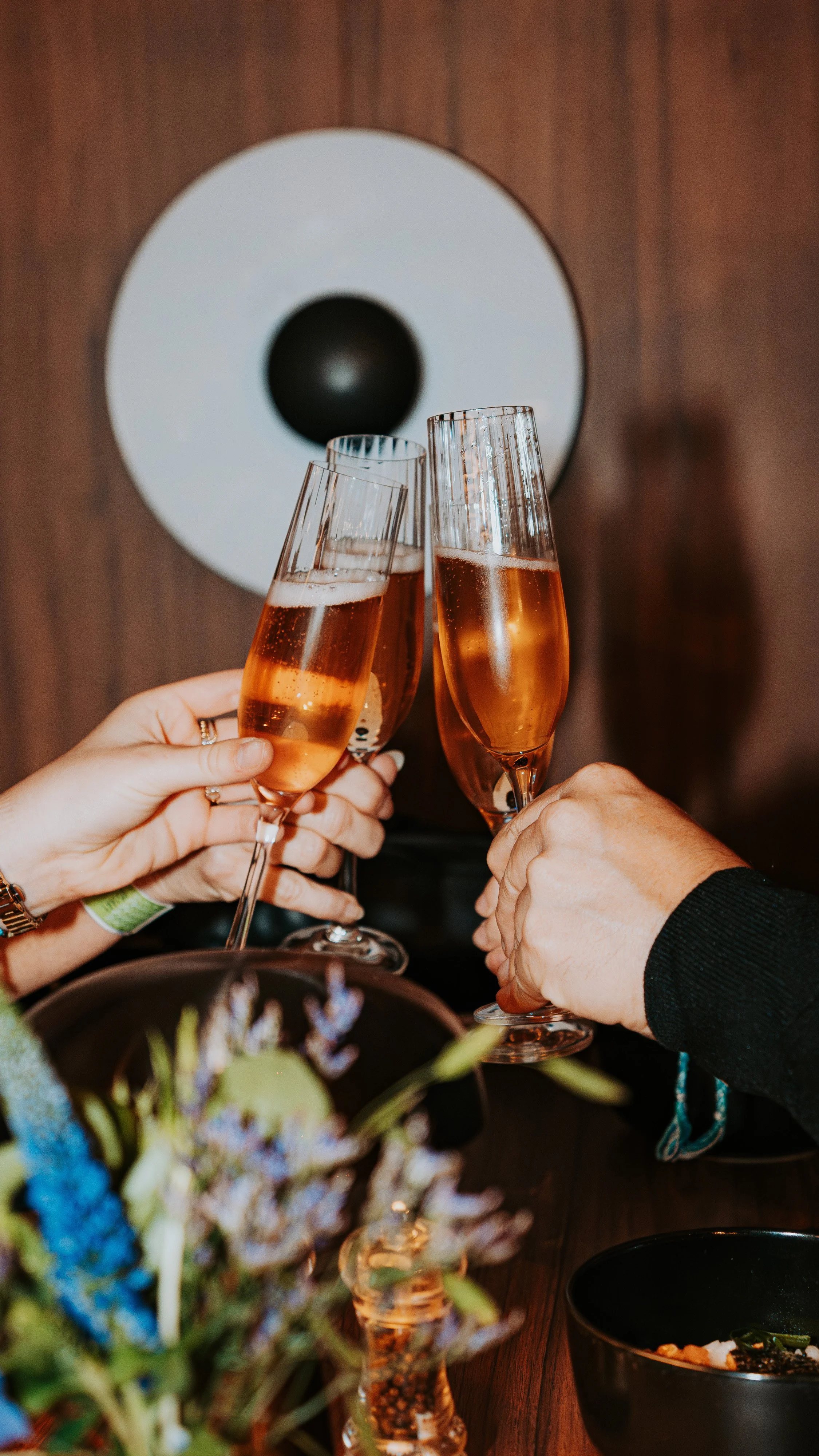 People toasting with glasses of rosé wine at a dinner table.