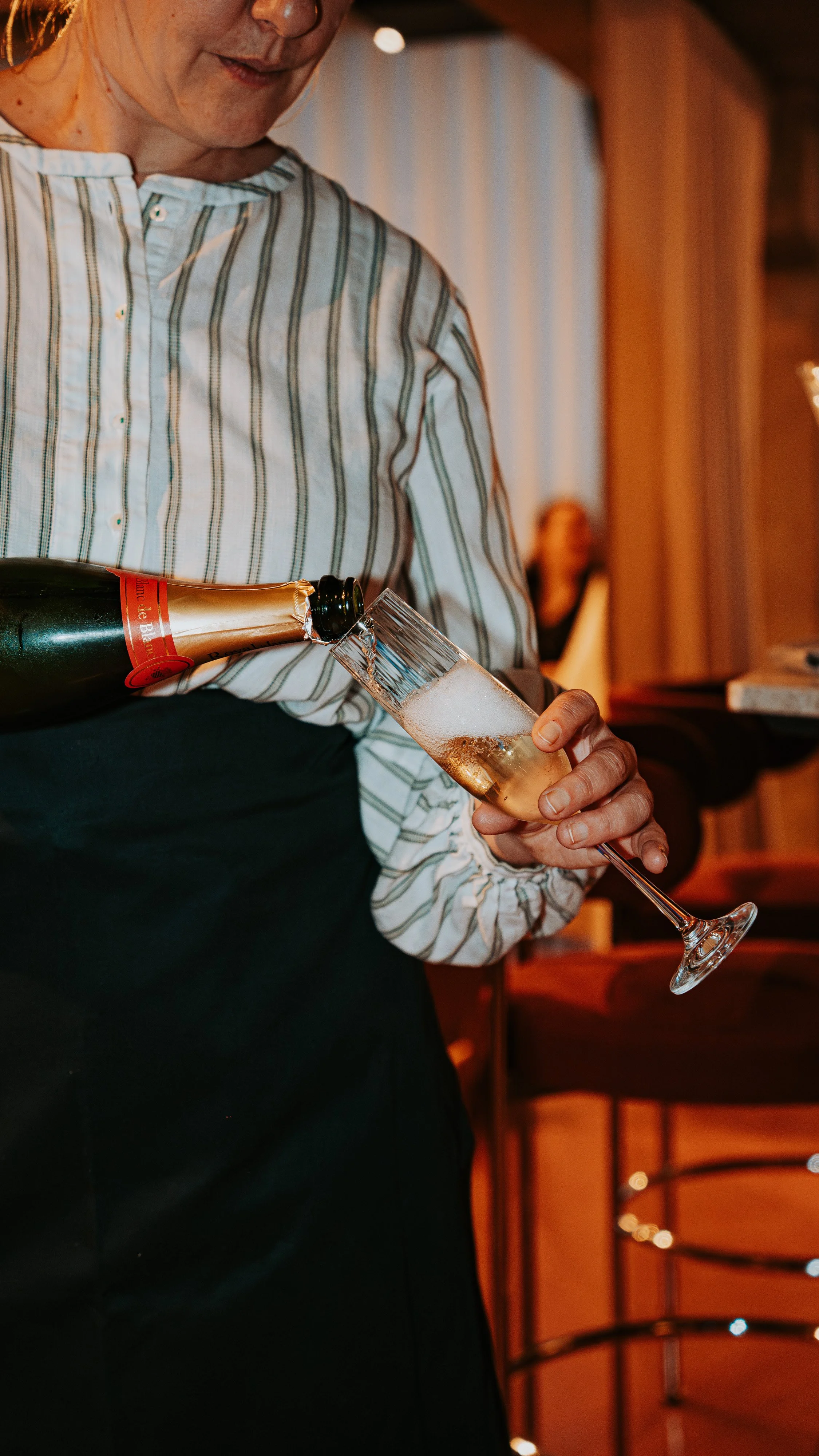 Person pouring champagne into a flute in a dimly lit room.