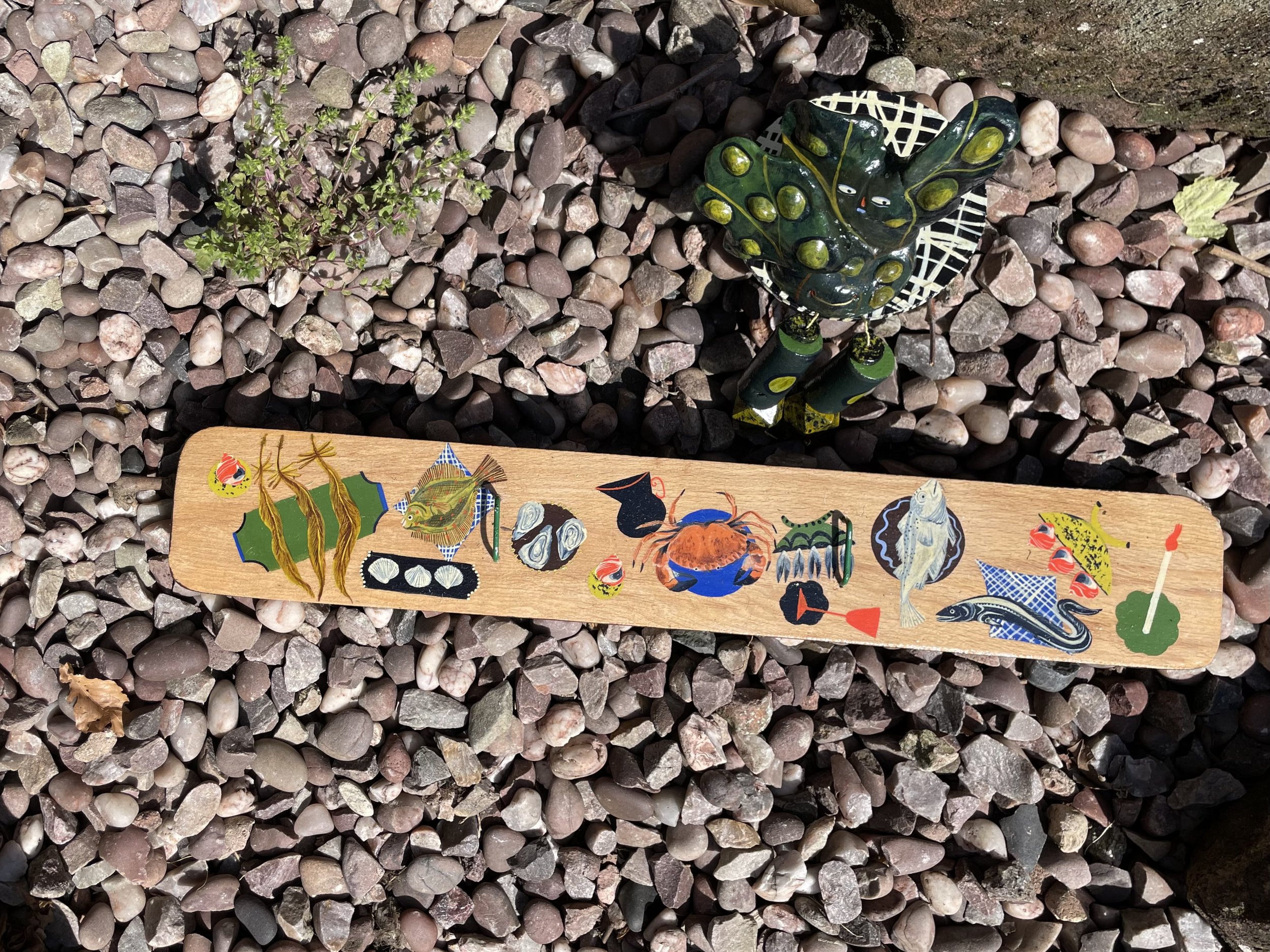 'BLADDERWRACK'S FEAST' represents the gift of food that the Mersey offers; the river drawing people closer as a place of sustenance before major industrial pollution.  ‘Bladderwrack’ sits at a table abundant with brown crab, oysters, cockles, mussels