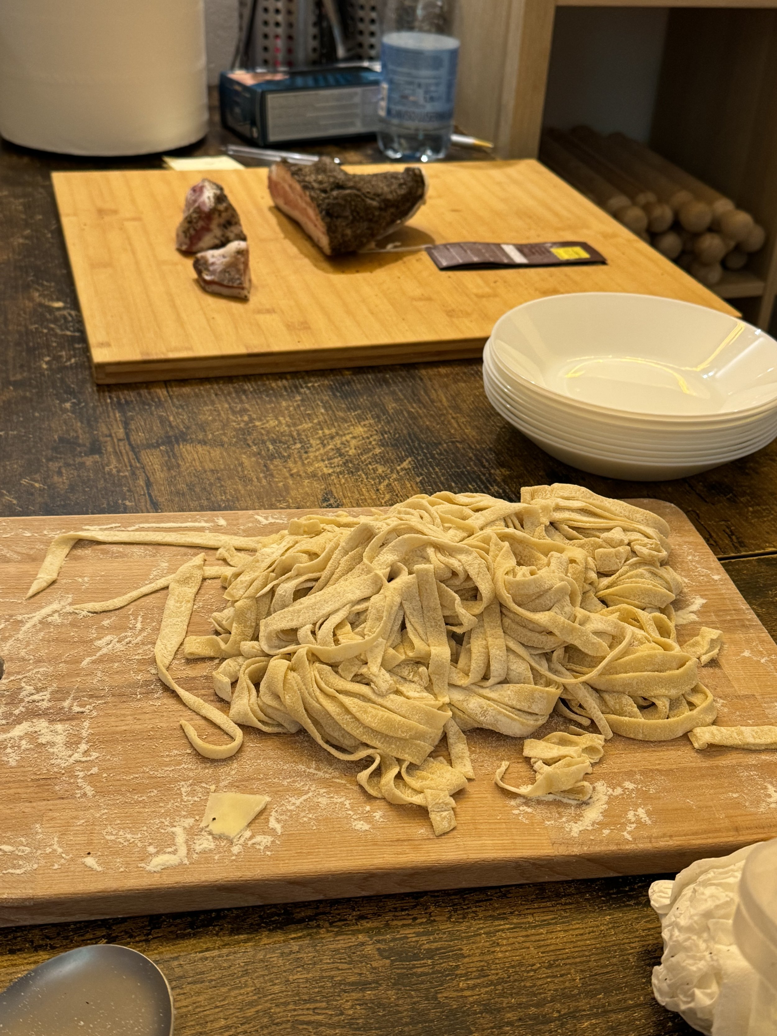 Fresh homemade pasta noodles on a wooden cutting board with flour dusting.