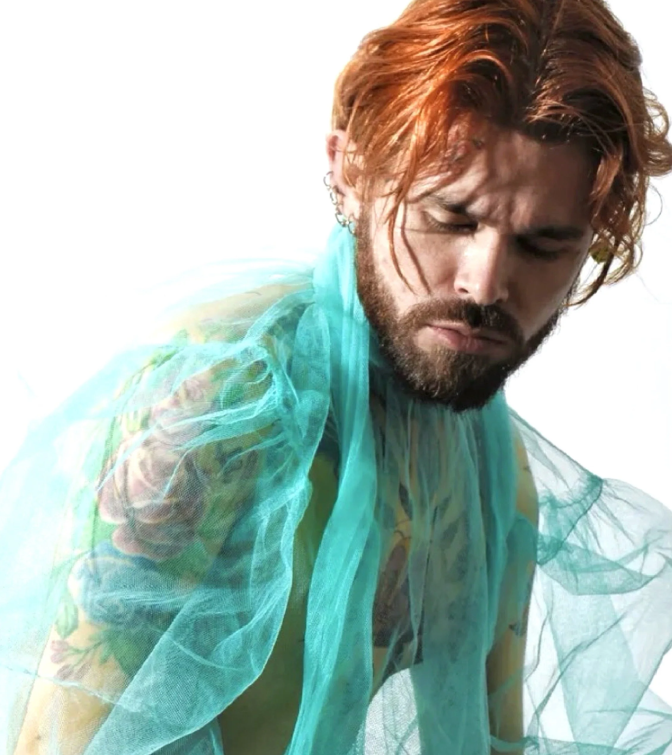 Premier plan d'une personne avec des cheveux roux, portant une chemise en tissu léger de couleur turquoise, en train de regarder vers le bas.