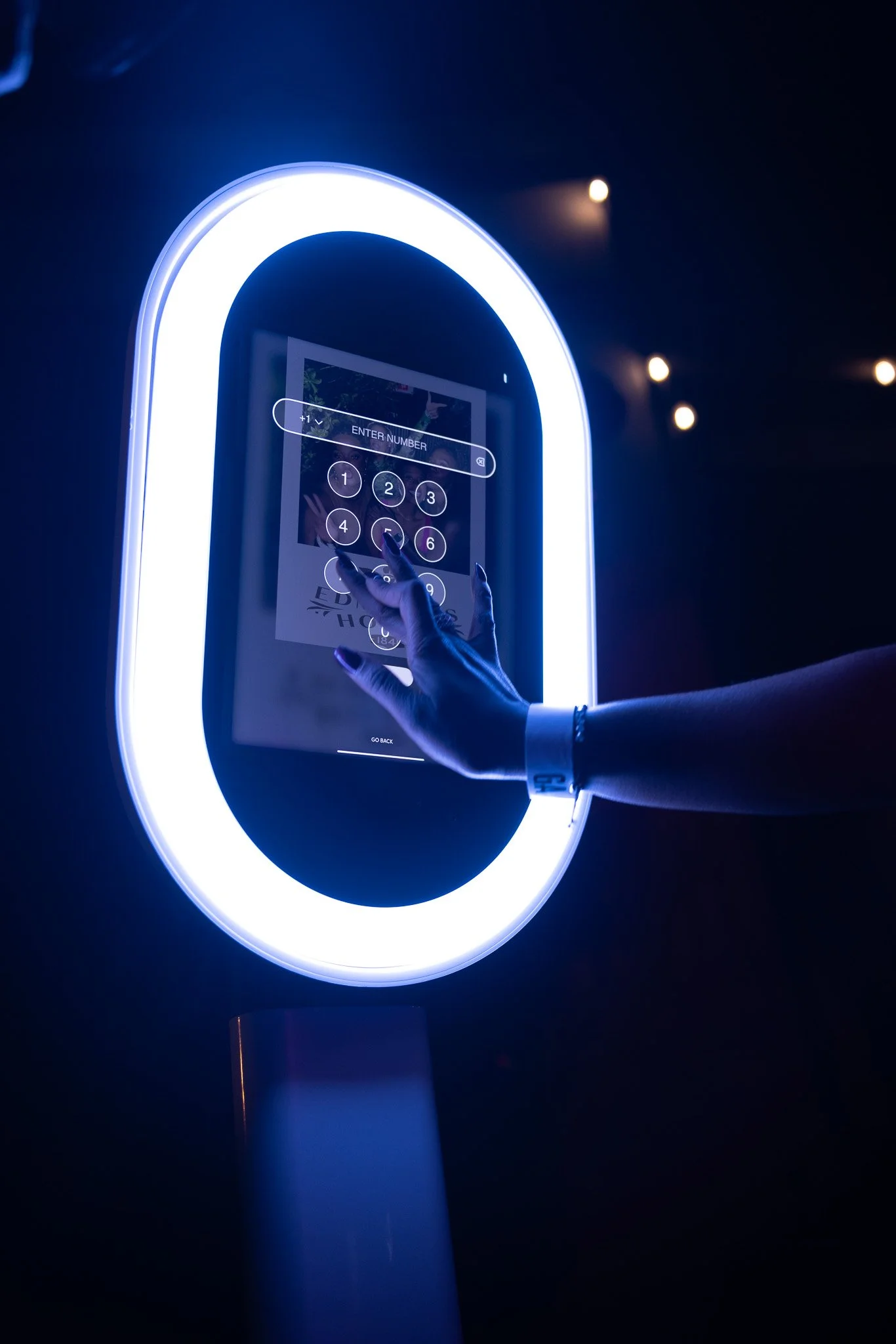 Person pressing buttons on a digital kiosk with a glowing white and blue circular frame.