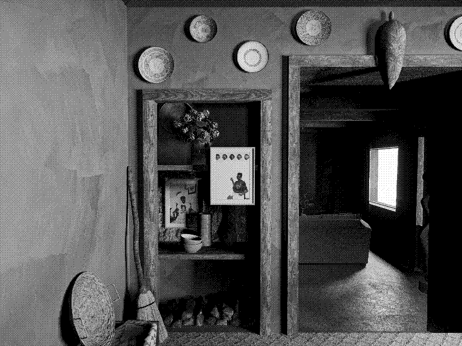 A view through a rustic wooden doorway into a living room decorated with artwork, a fireplace, a Christmas wreath, and a sofa, with a flat-screen TV visible in the background.