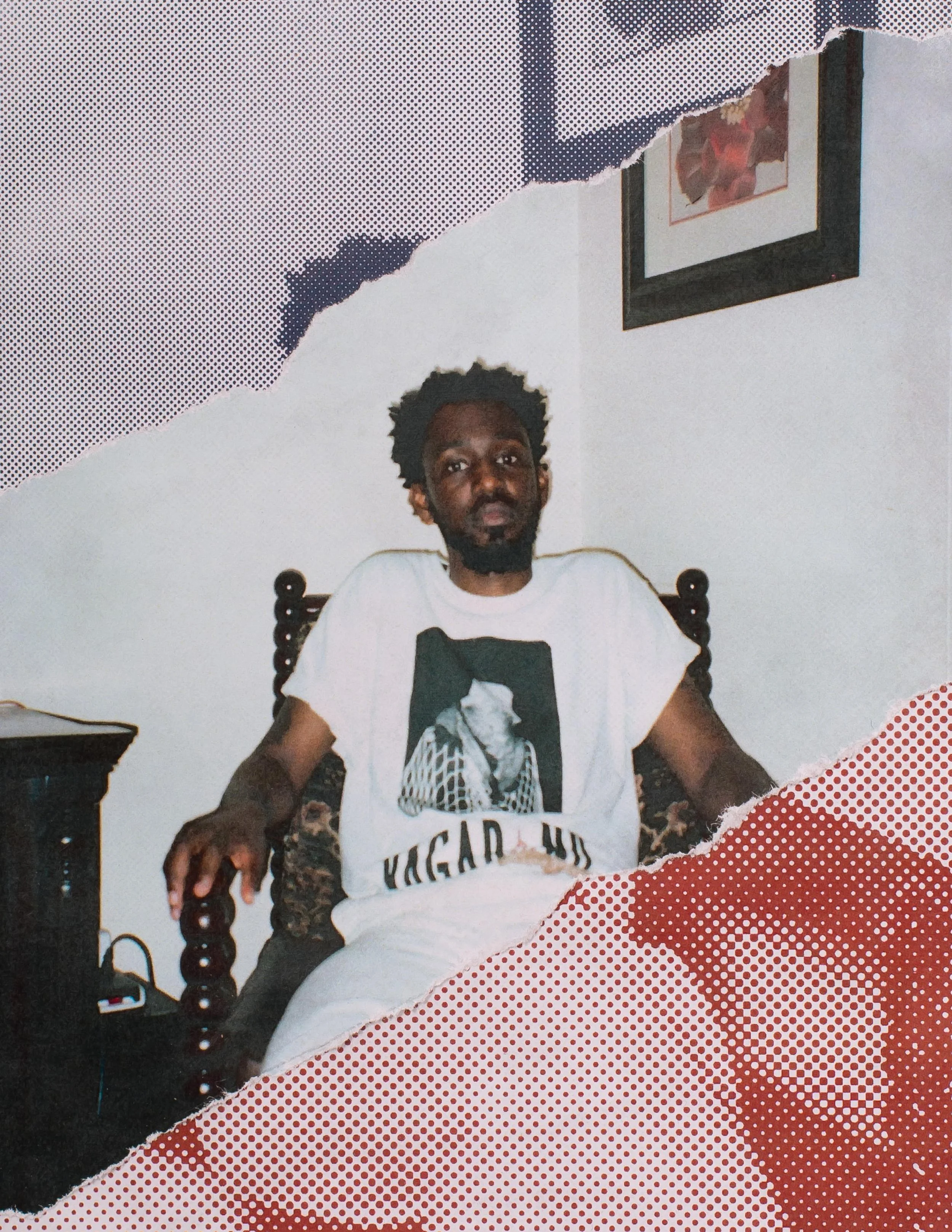 A man with dark hair and beard sitting on a wooden chair, wearing a white t-shirt with a graphic and text, in a room with pictures on the wall, with torn paper design overlay.