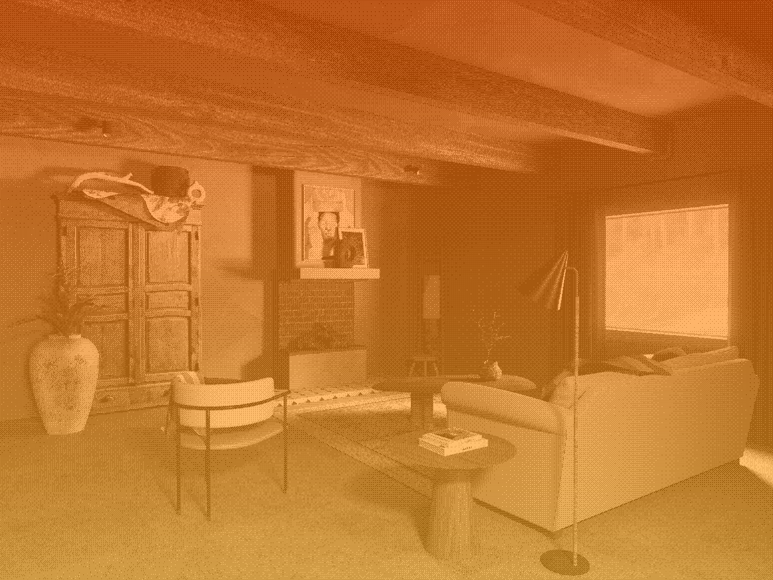 A cozy living room with a large sofa, an armchair, a wooden cabinet, a large vase, a fireplace, and a TV, with framed photographs above the fireplace and a window with a curtain.