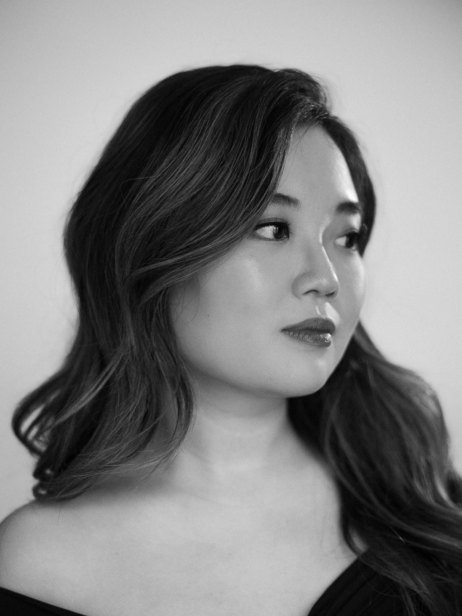 Black and white portrait of a woman with long wavy hair looking to the side.